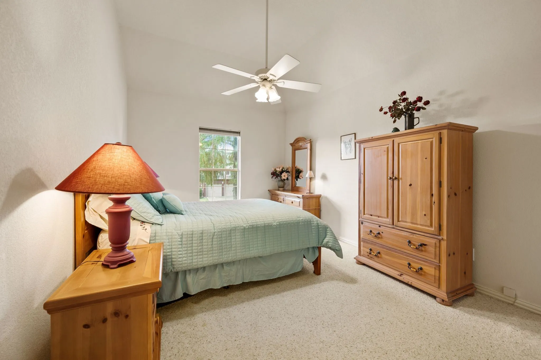 Vaulted ceiling with ceiling fan, window with natural light, and textured wall finish