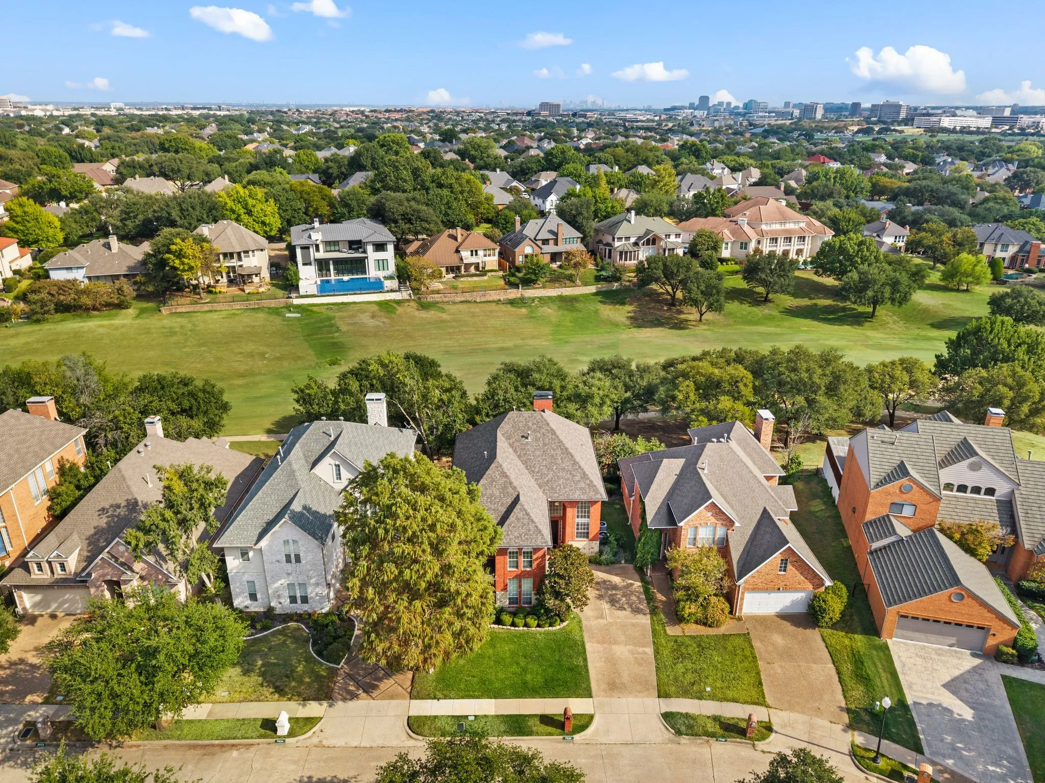 Residential neighborhood with mature trees and a manicured green space