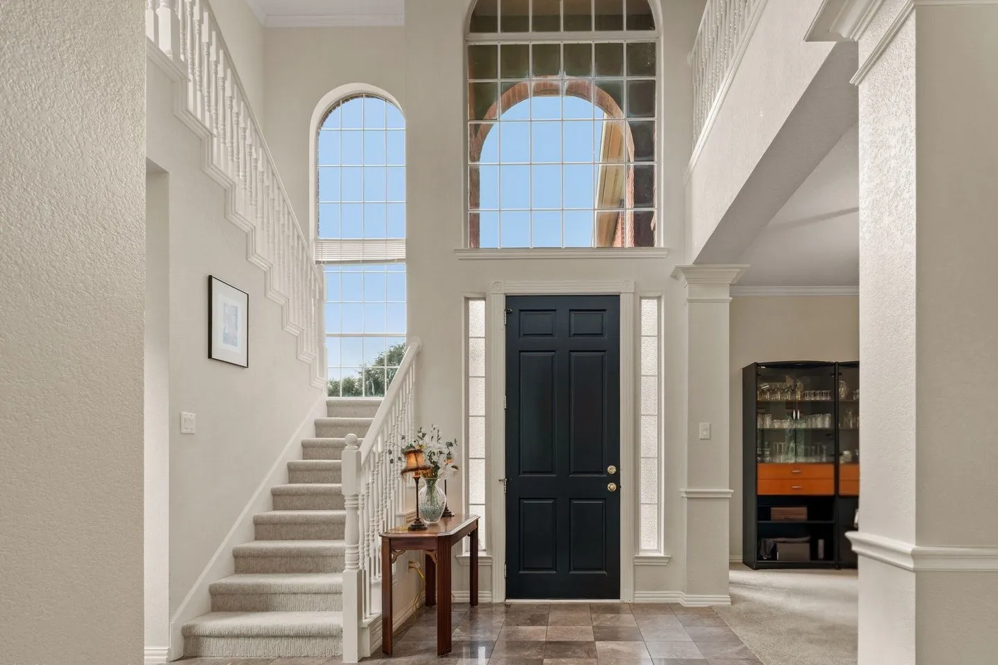 Two-story foyer featuring an arched transom window, two-story arched window, paneled entry door, and tiled flooring