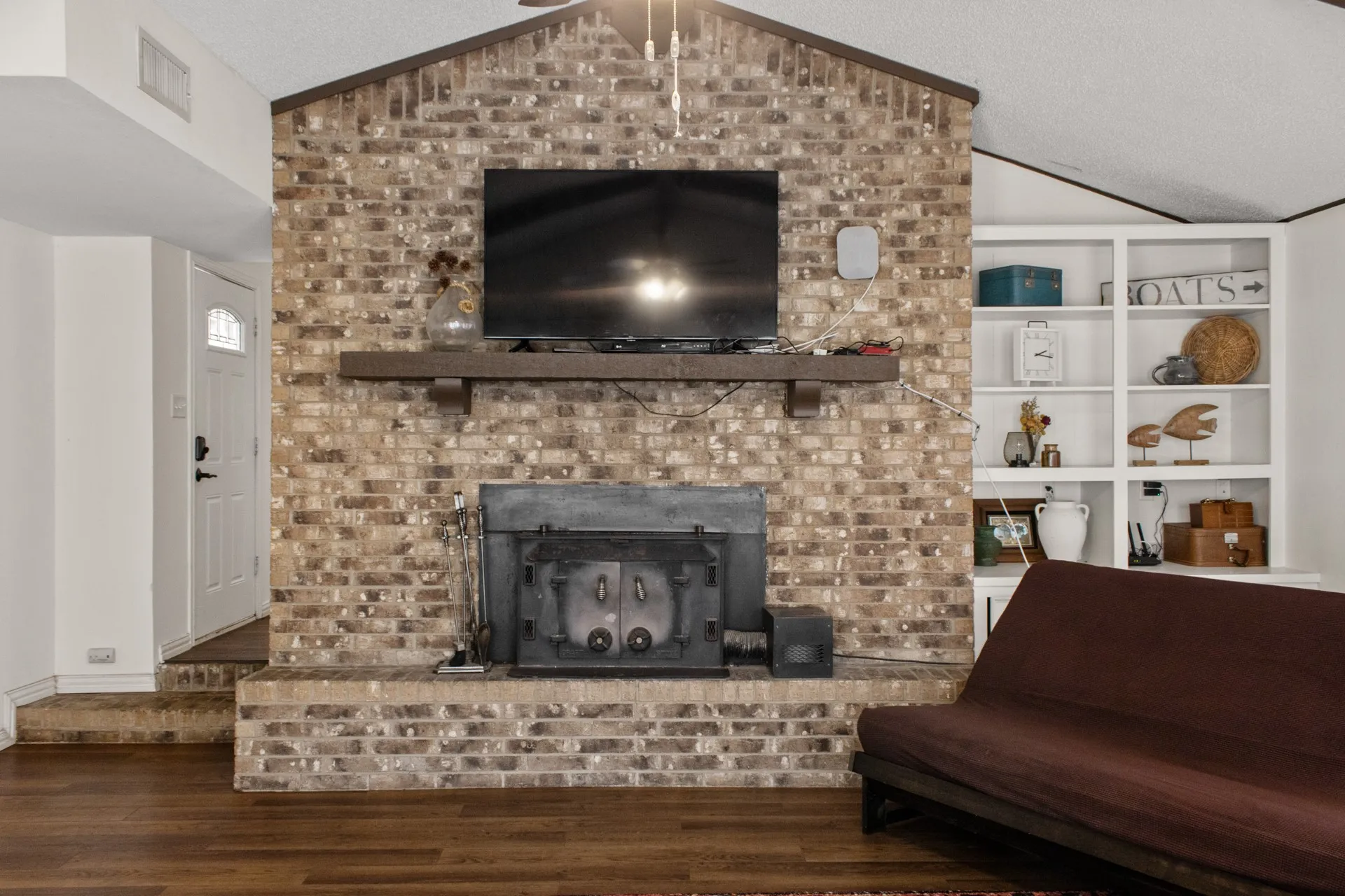 Brick-faced fireplace with a substantial wood mantel, integrated firebox, and built-in shelving