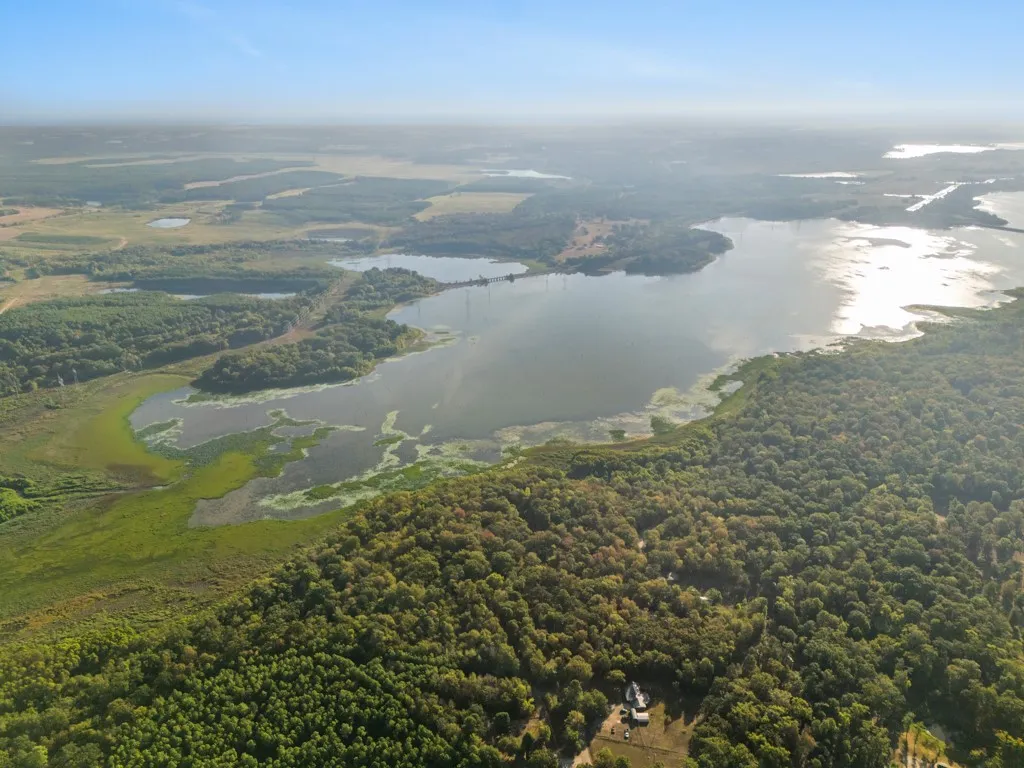 Expansive lake frontage with surrounding wooded areas and open fields