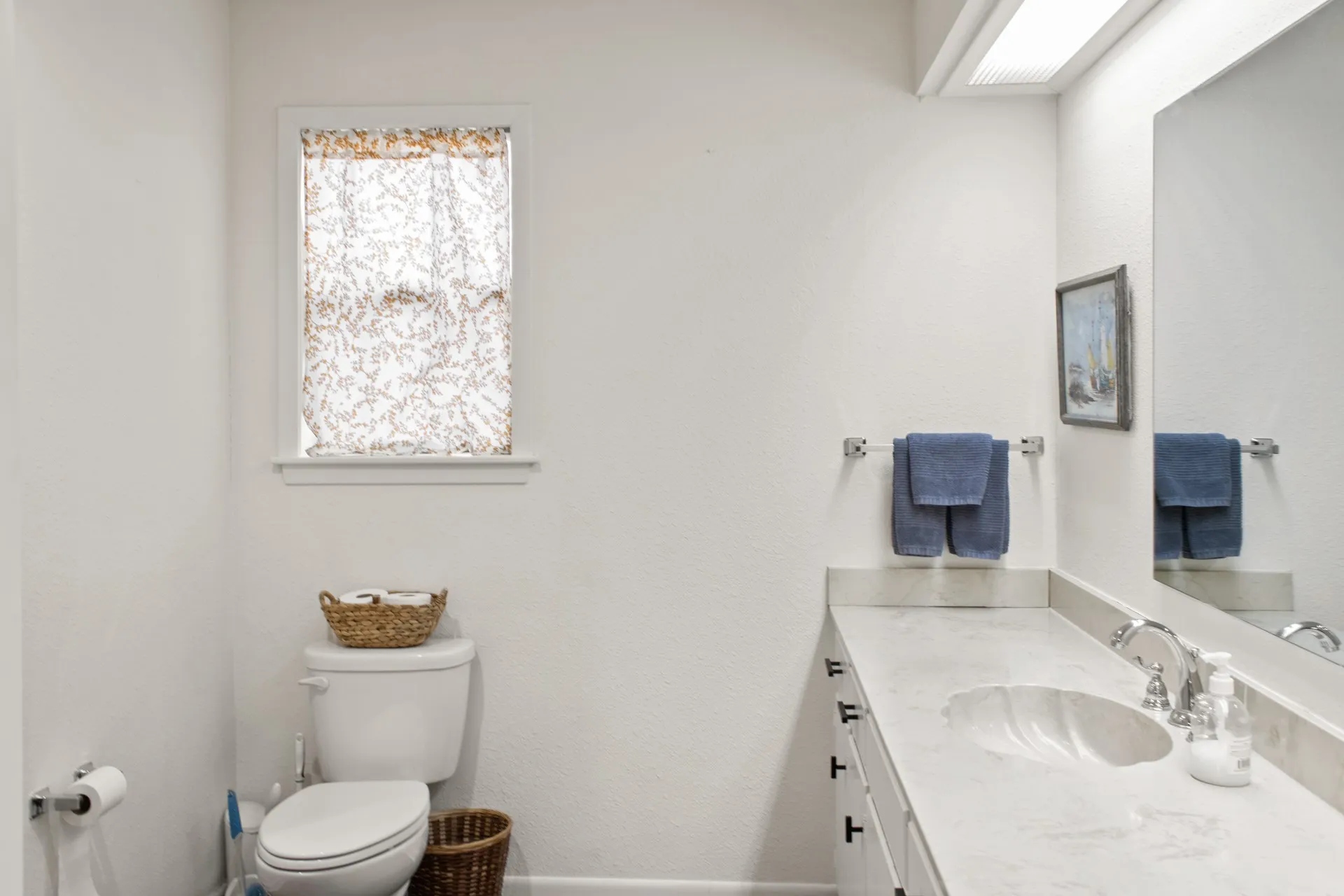 Vanity with an integrated basin and a polished chrome faucet, under-cabinet storage, and a framed mirror