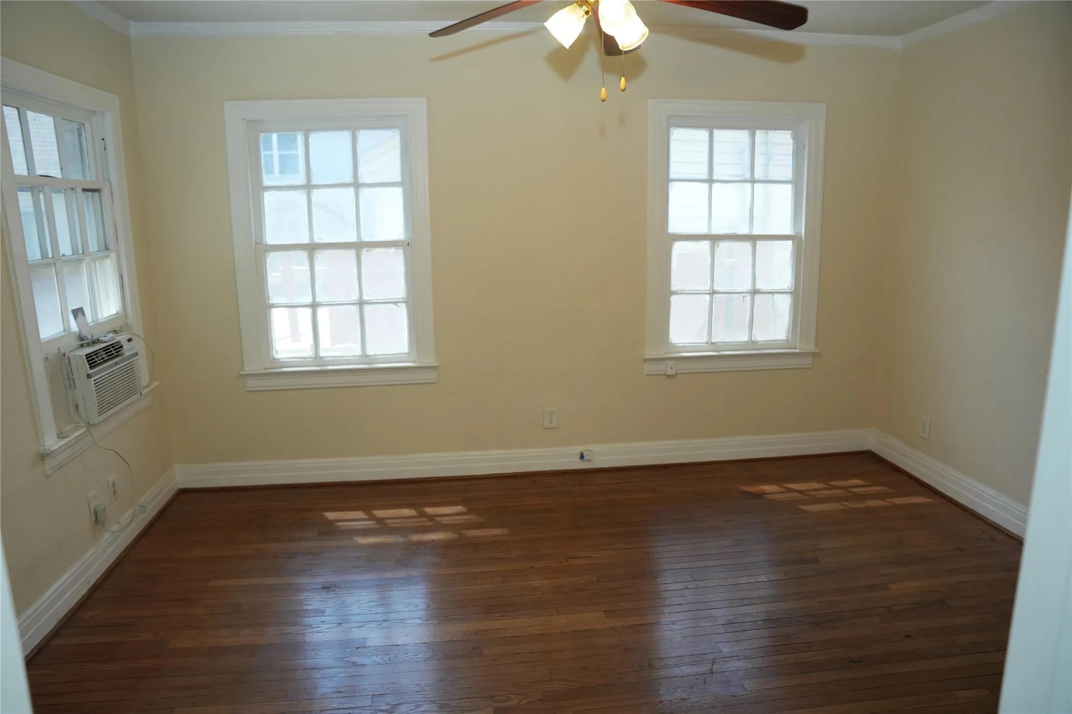 Bedroom in front duplex with dual windows and hardwood floors.