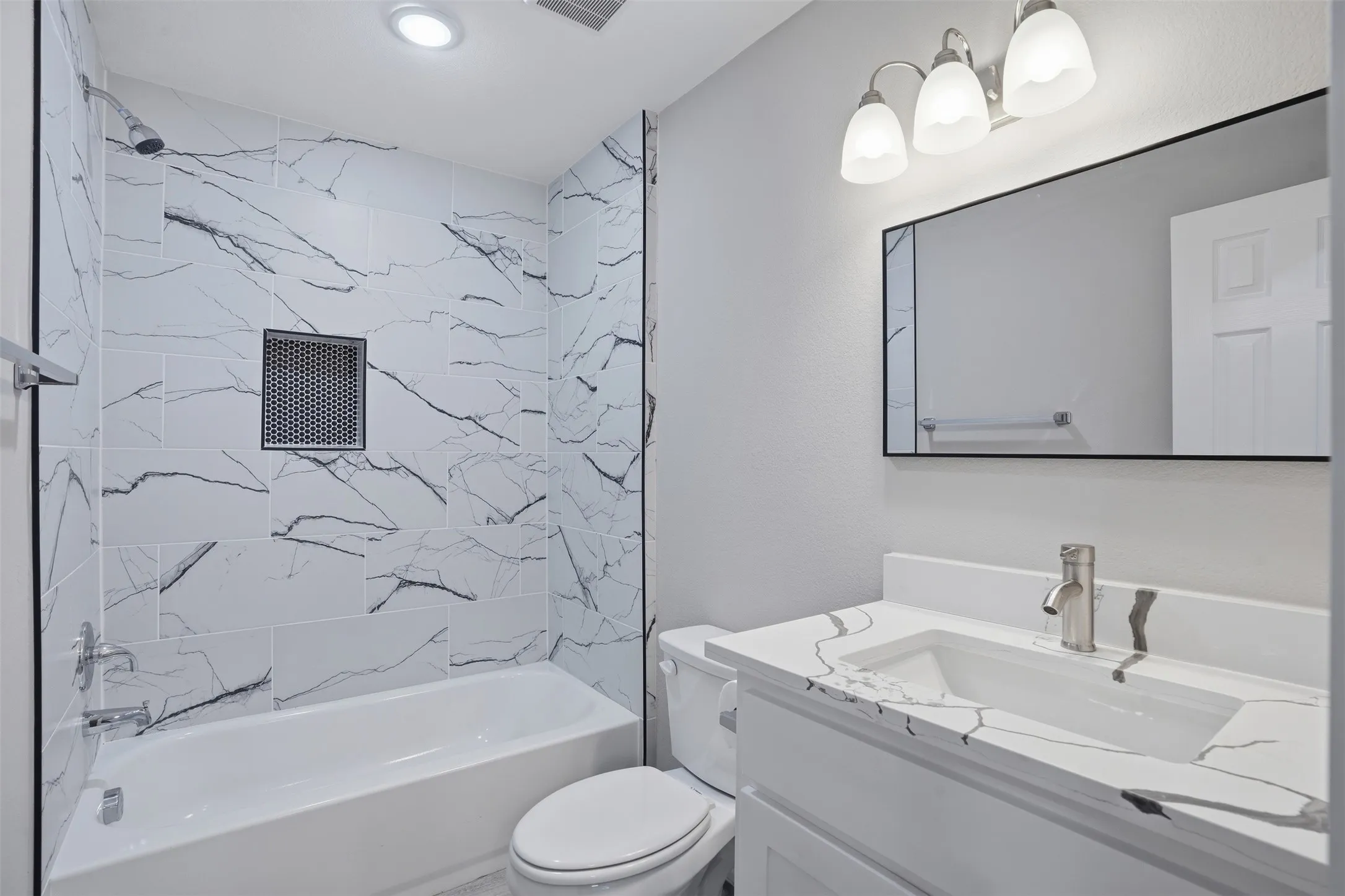 Contemporary bathroom featuring a white vanity with integrated sink, patterned countertop, and a sleek rectangular mirror