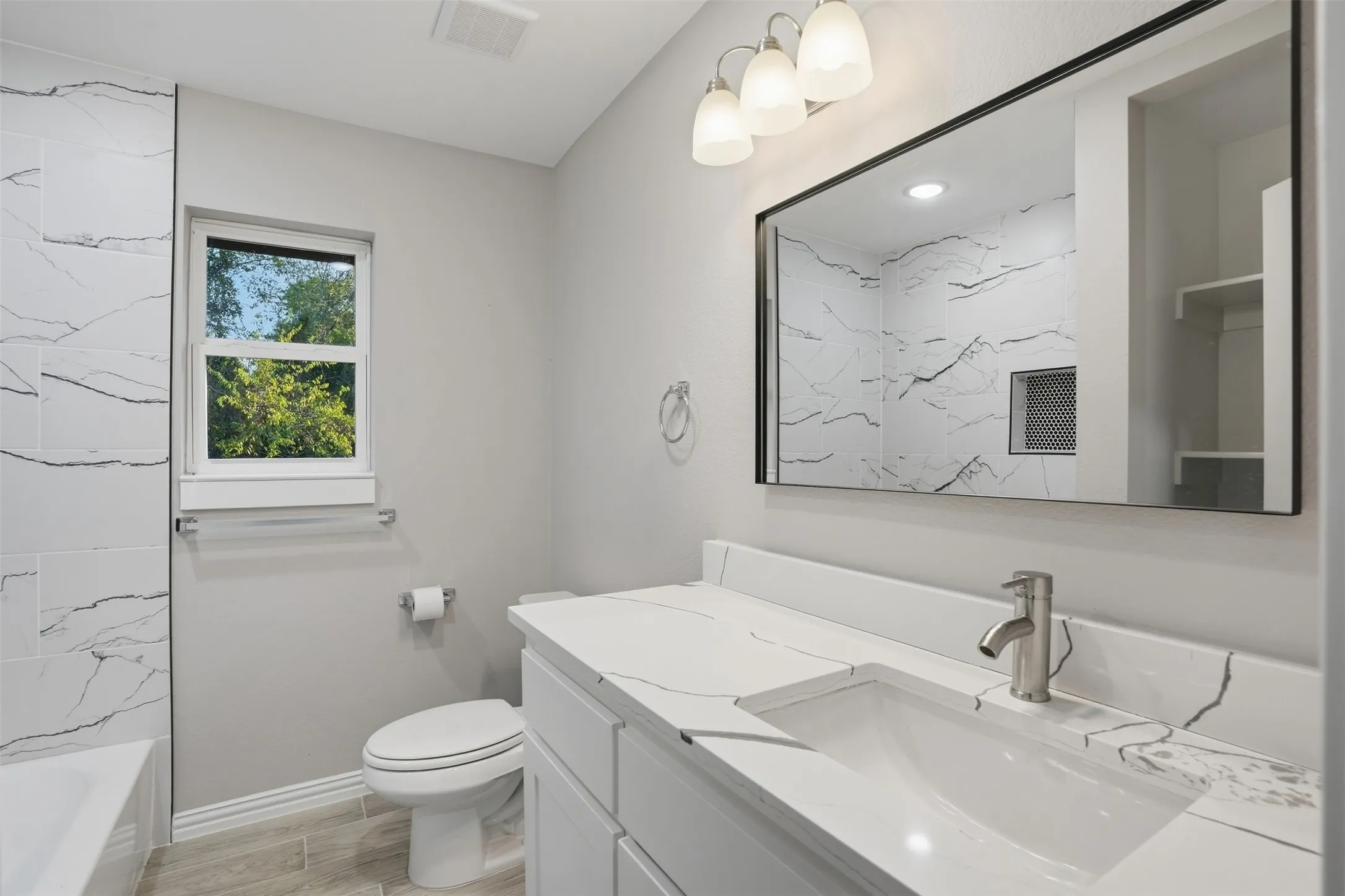 Bathroom featuring a single vanity with stone-finish countertop, undermount sink, and brushed nickel faucet