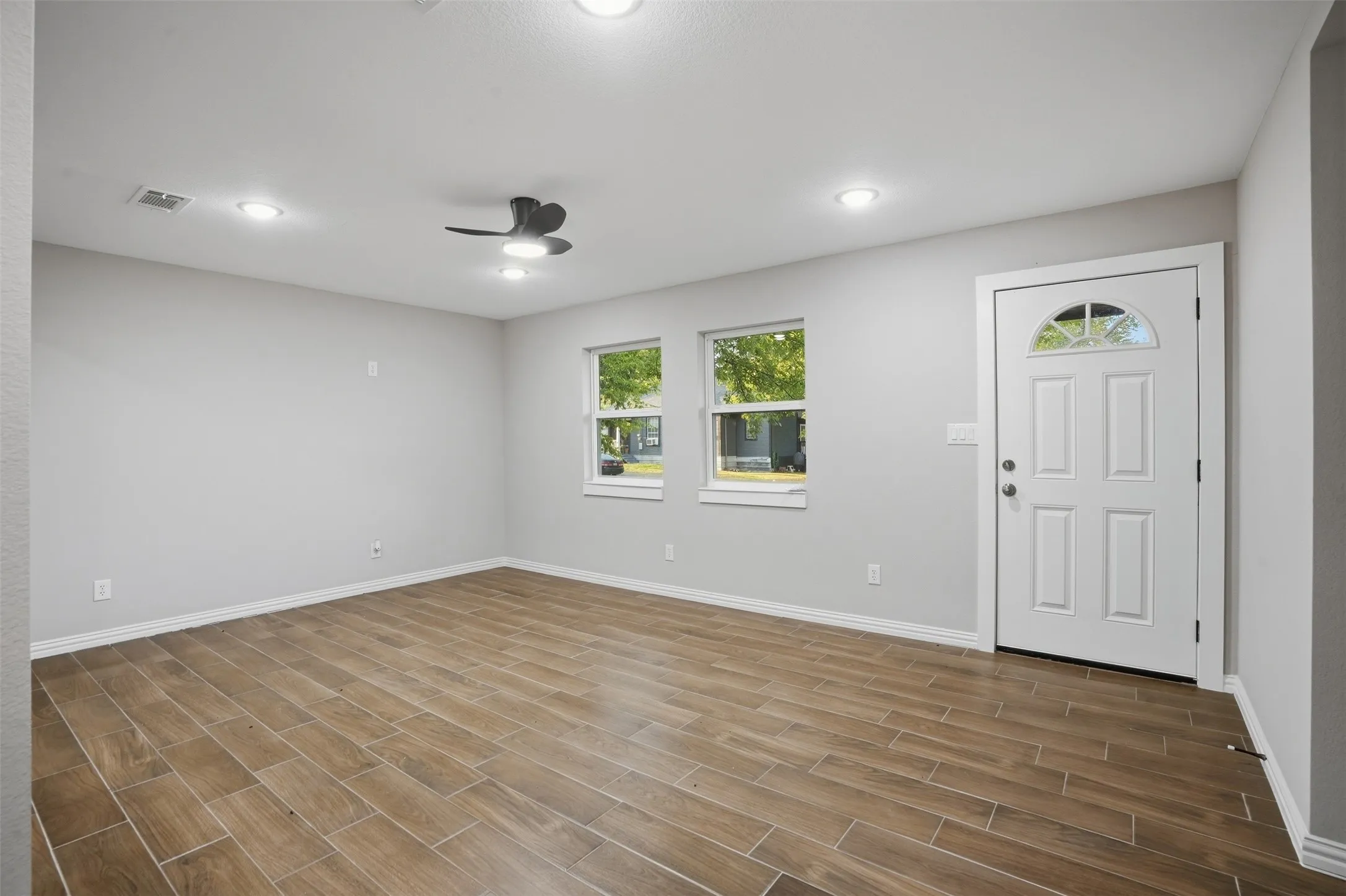 Wood-finish tile flooring throughout, recessed ceiling lighting, and a contemporary ceiling fan