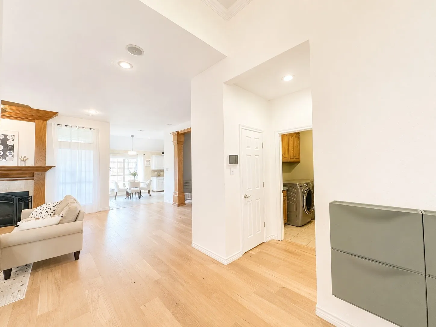 Hardwood flooring throughout, recessed lighting, fireplace with wood mantel, laundry area with cabinetry, and an open layout
