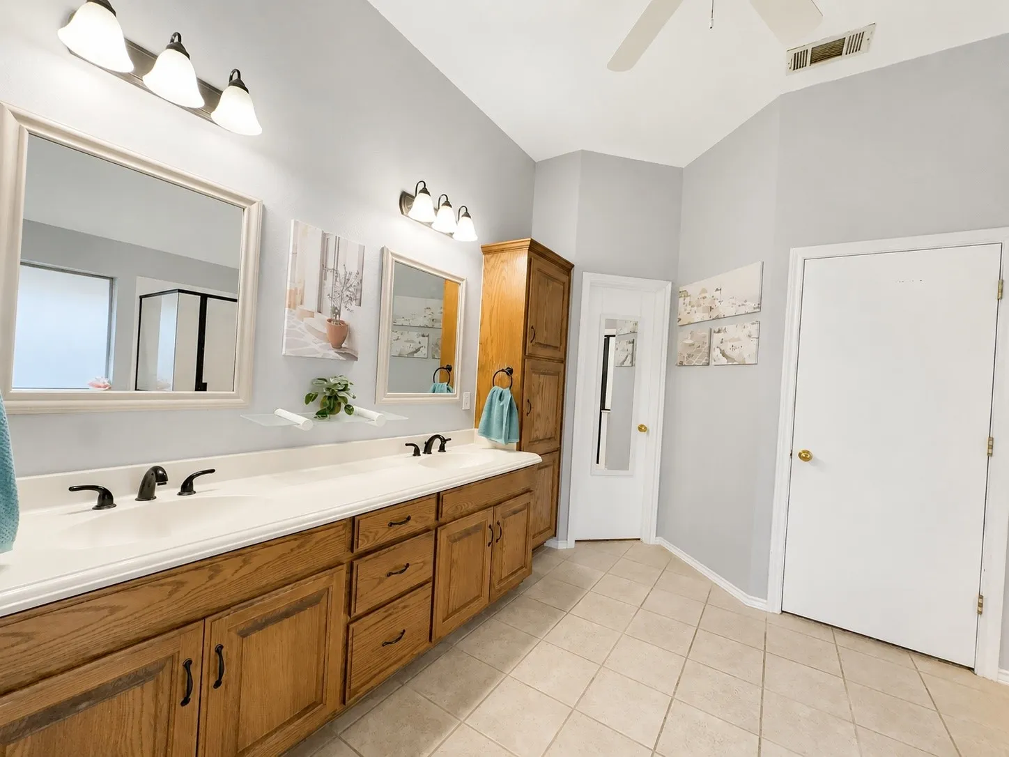 Dual vanities with integrated sinks, wood-finish cabinetry, and matte black fixtures