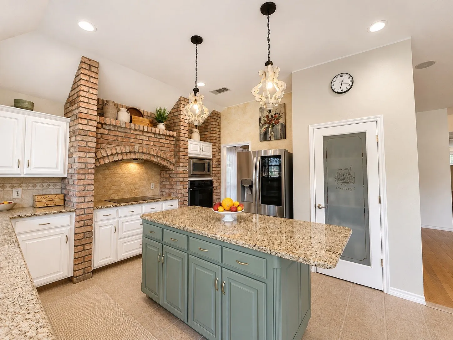 Kitchen featuring a brick archway with integrated lighting, a substantial island with a granite countertop, white cabinetry with gold-toned hardware, and recessed ceiling lights