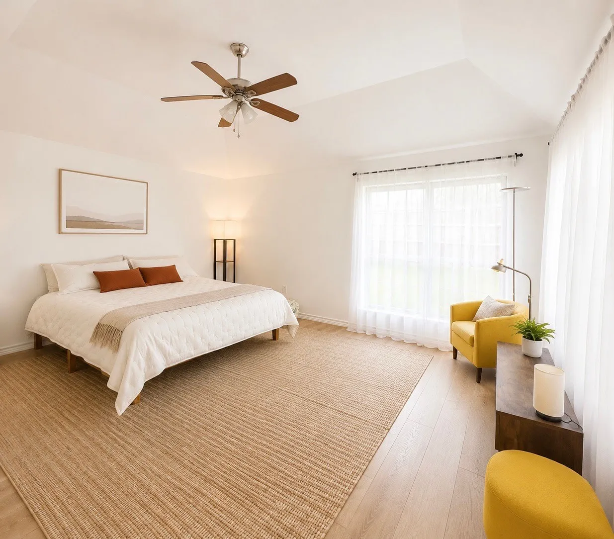 Vaulted ceiling with a ceiling fan, light wood-finish flooring, and large window with sheer white curtains