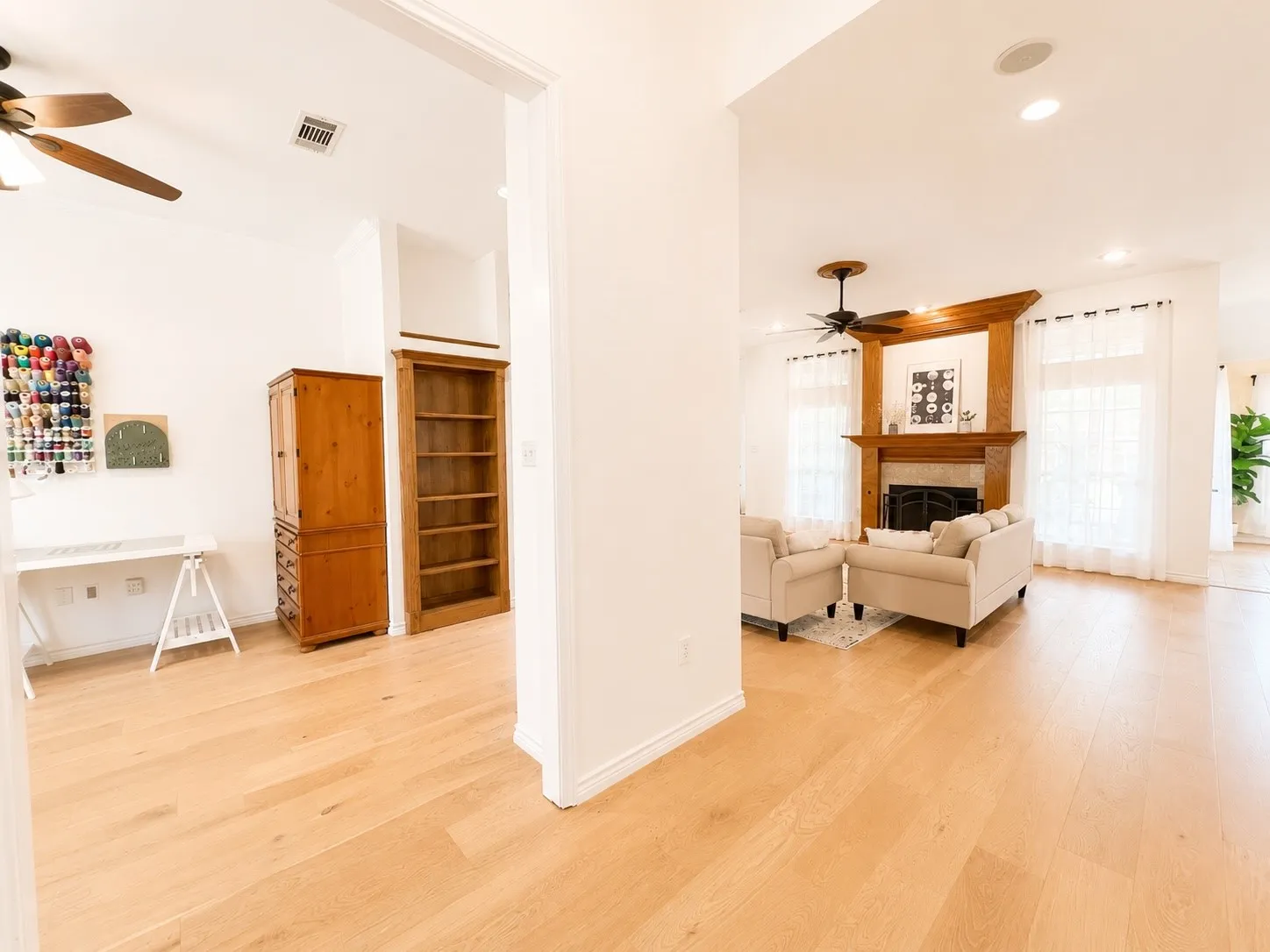Light wood-finish flooring throughout, living area with a wood-mantel fireplace, recessed lighting, and ceiling fans