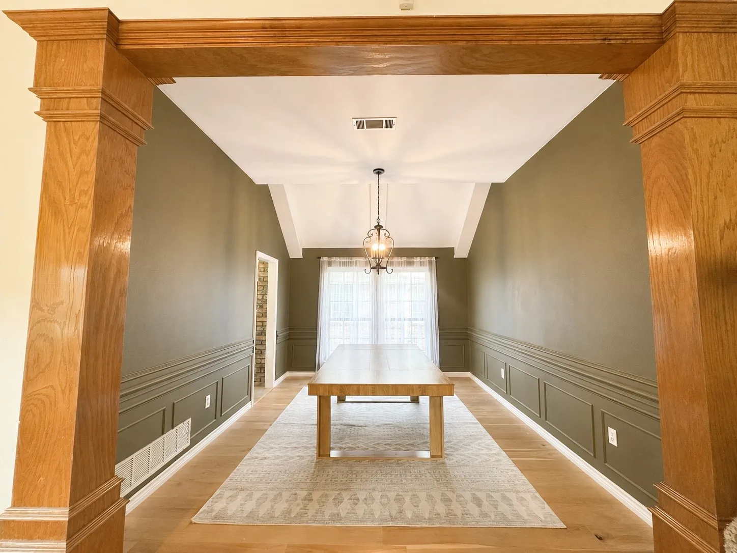 Wood-finish flooring, accent paneling, and an exposed beam entryway define this interior space