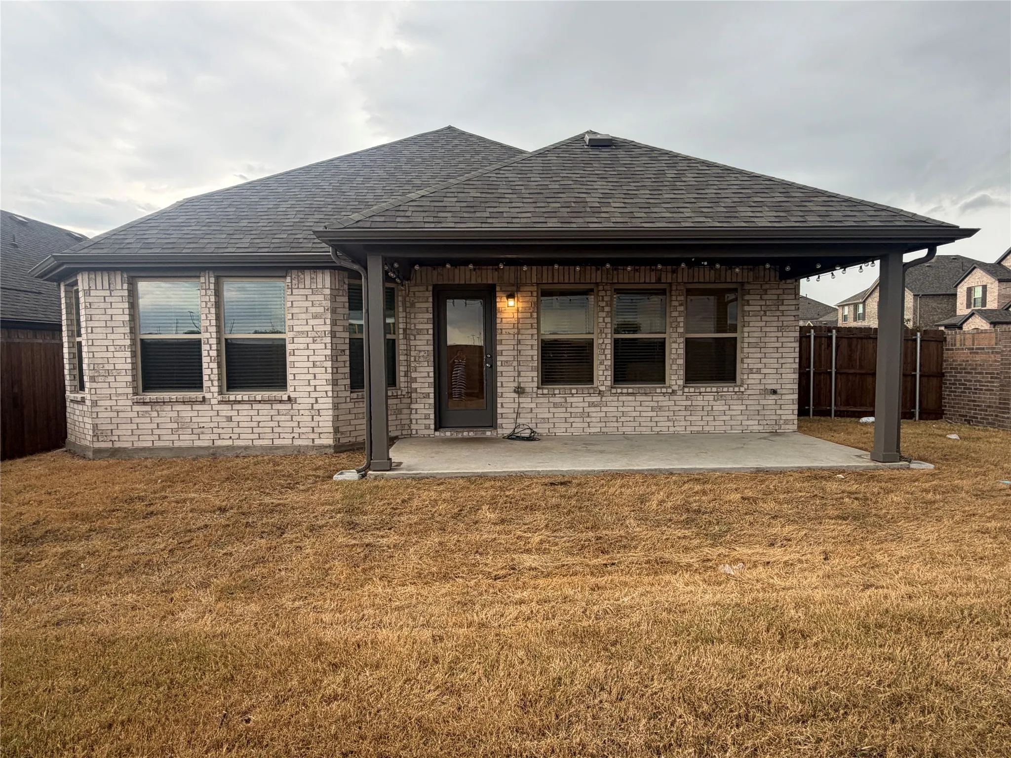 Brick exterior with a covered patio, concrete slab, and dark-framed windows