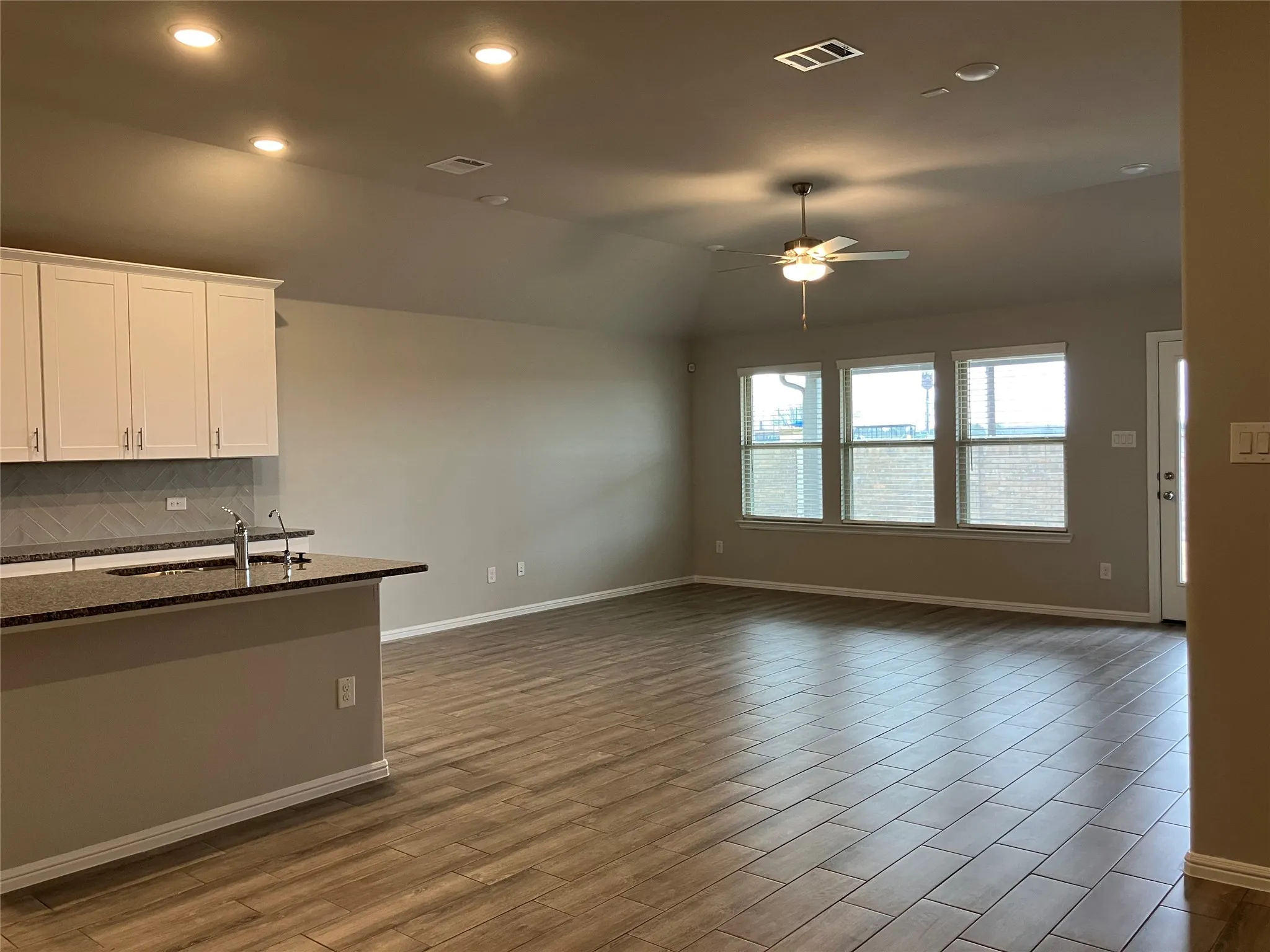 Open-concept living area featuring wood-finish tile flooring, recessed lighting, and a ceiling fan