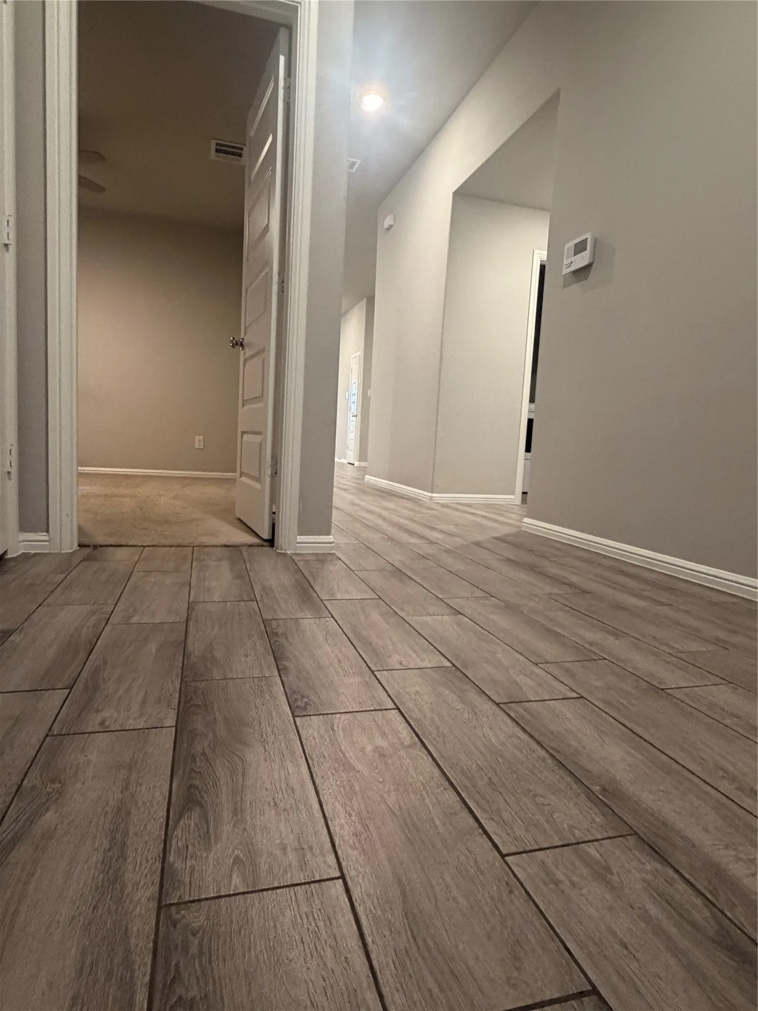 Wood-look tile flooring in a neutral tone, recessed ceiling lighting, light gray wall paint, and white baseboards