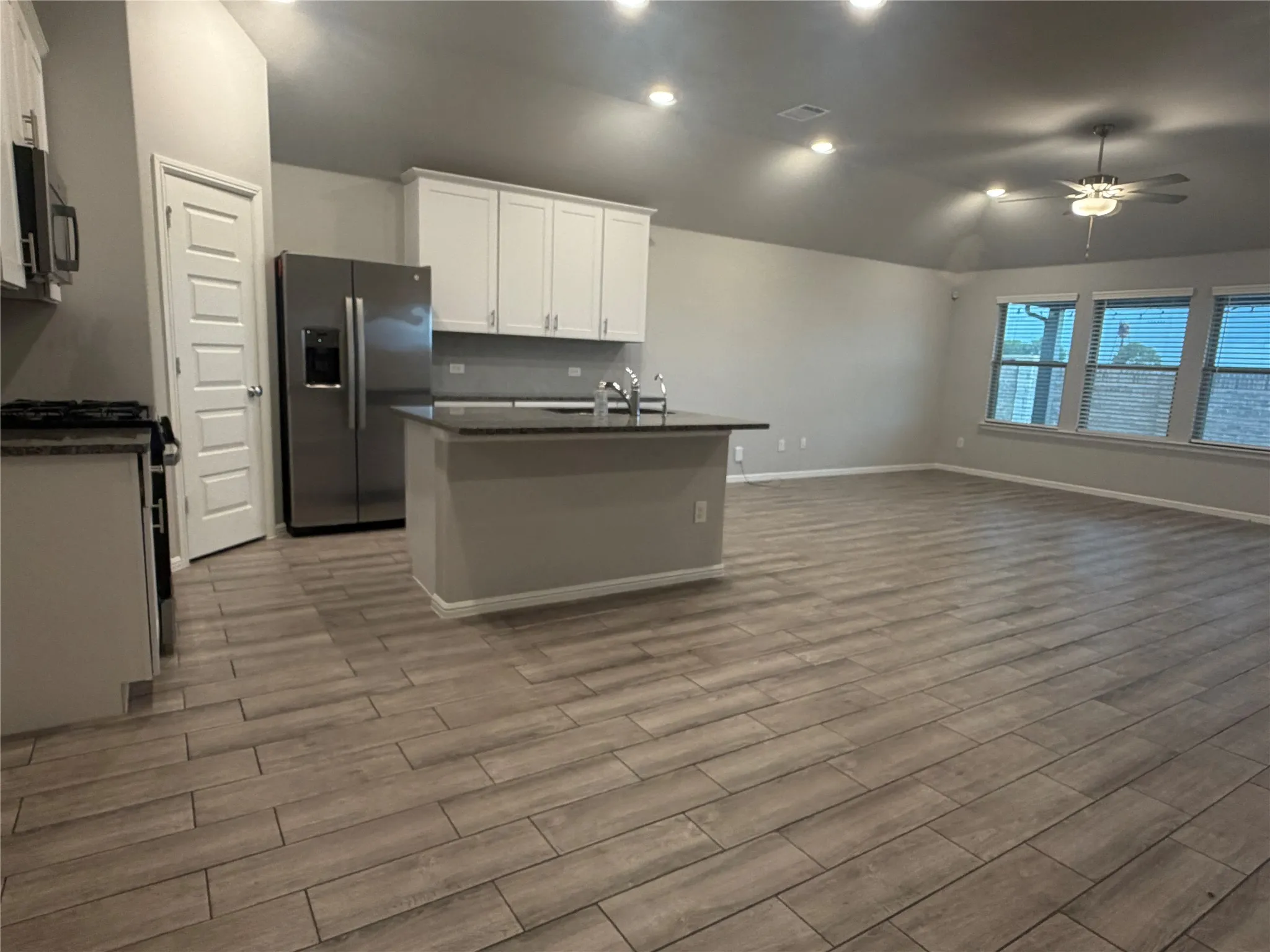 Open-concept living area featuring wood-finish tile flooring, recessed lighting, and a ceiling fan