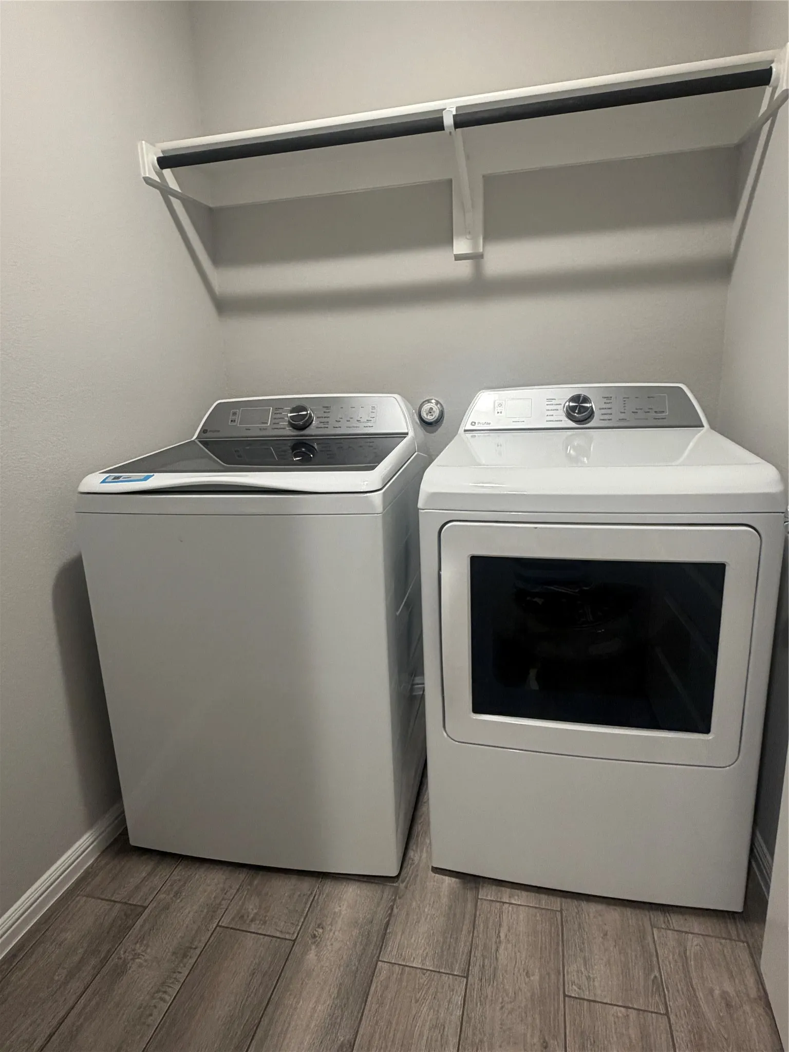 Laundry area featuring wood-finish flooring and integrated shelving