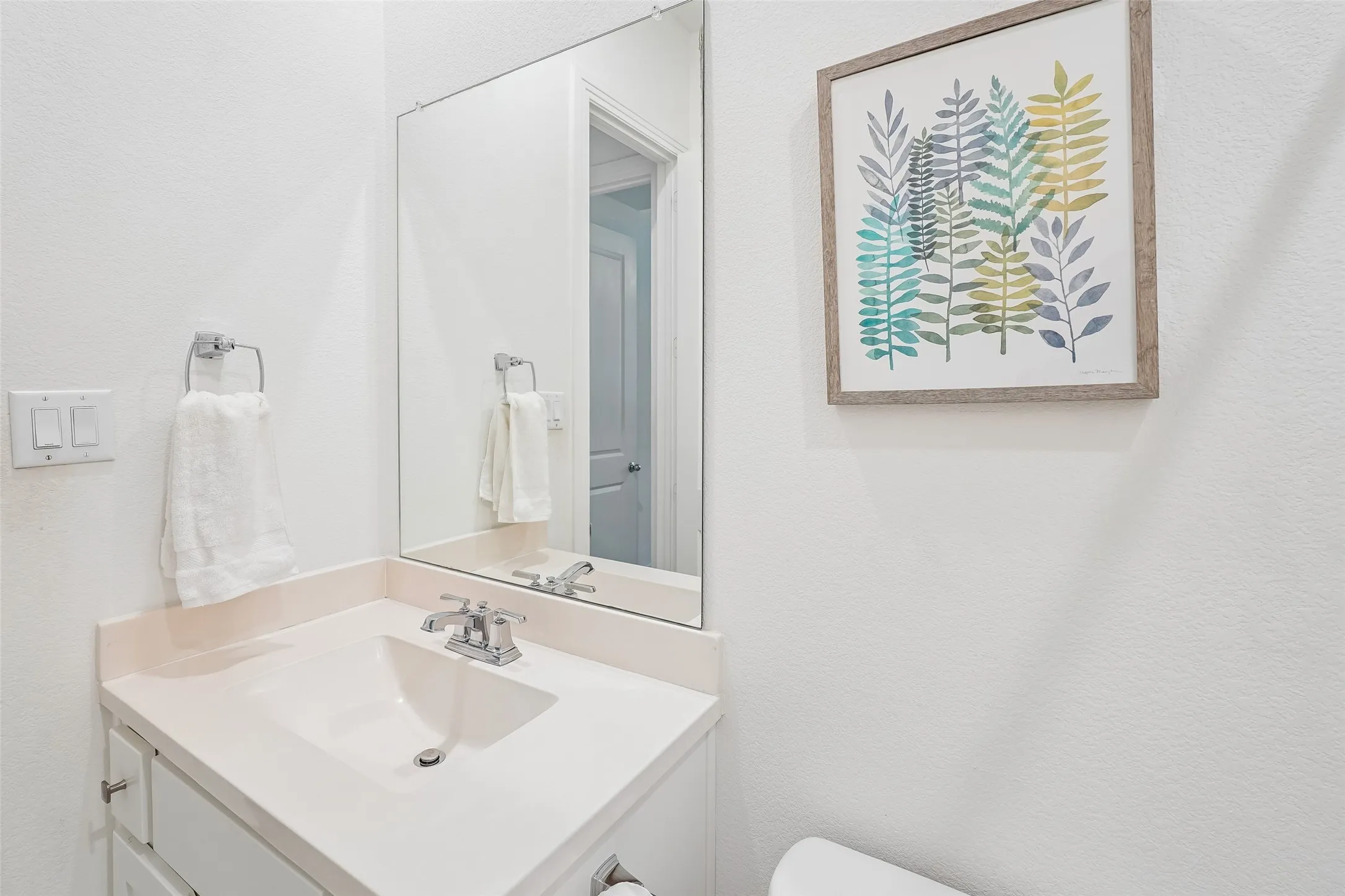 Vanity with an integrated sink, chrome faucet, and a large wall-mounted mirror