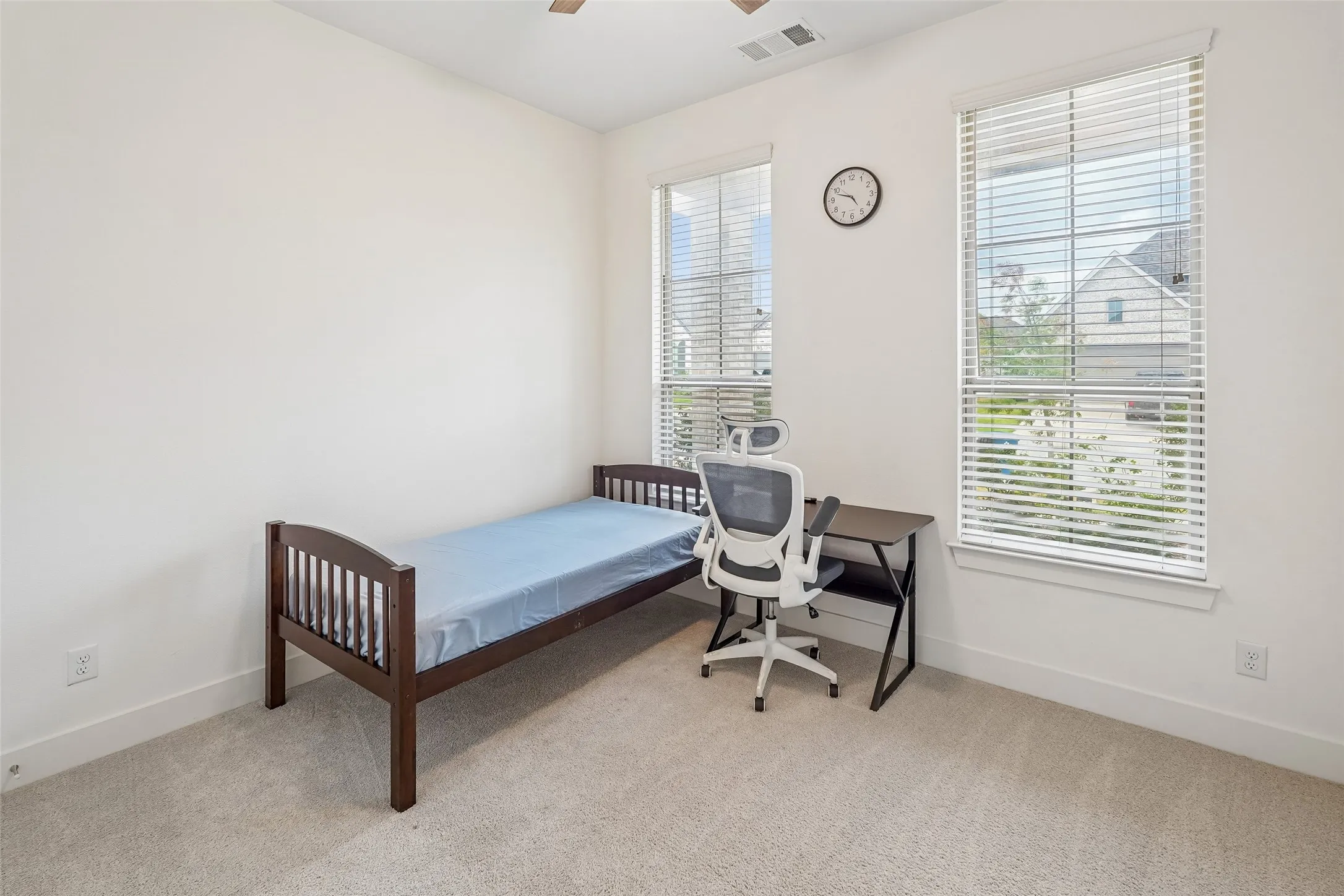 Plush carpet flooring, white painted walls, and two large windows with blinds