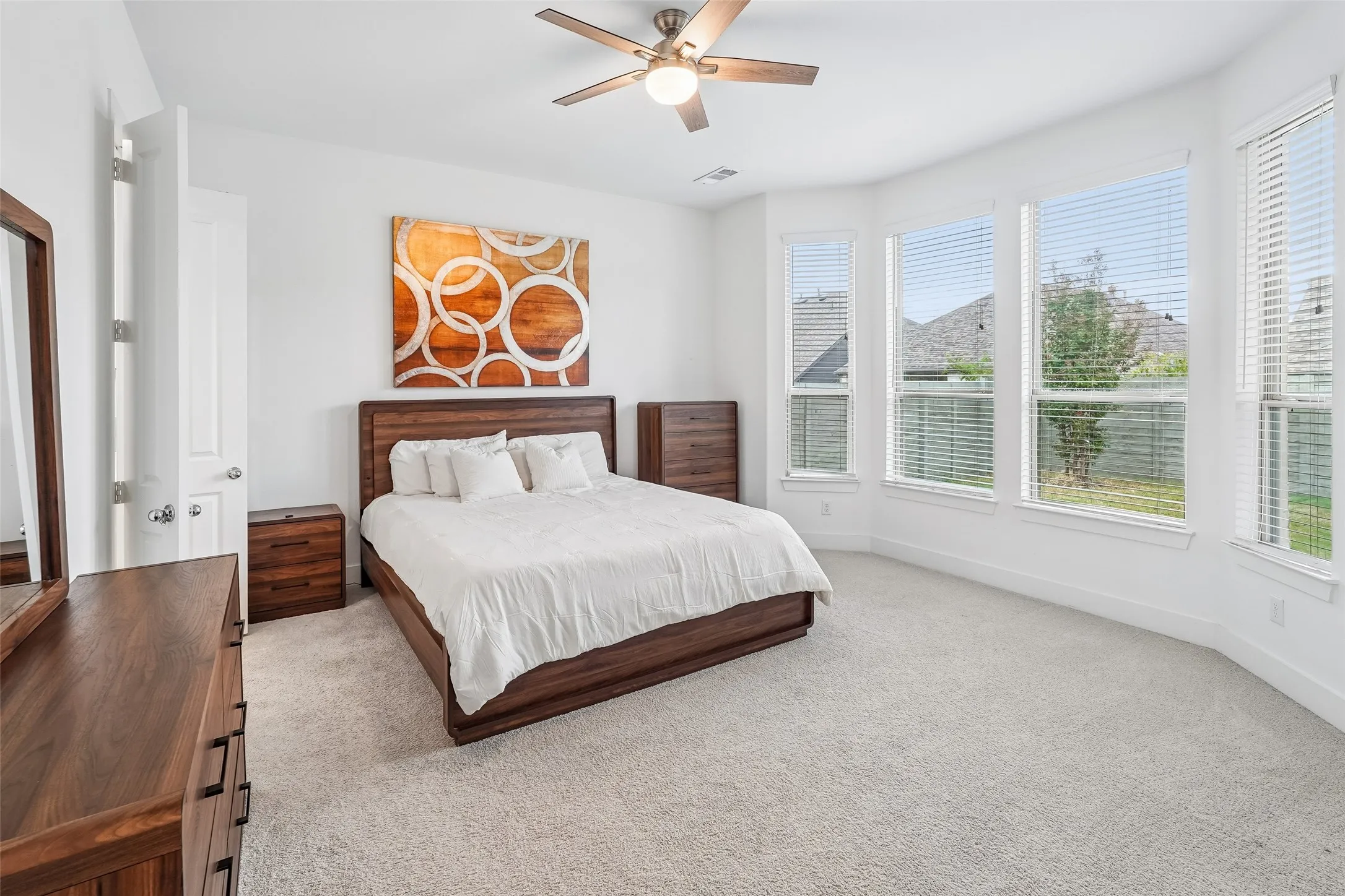 Plush carpet flooring, ceiling fan with integrated lighting, multiple windows with blinds, and white interior doors