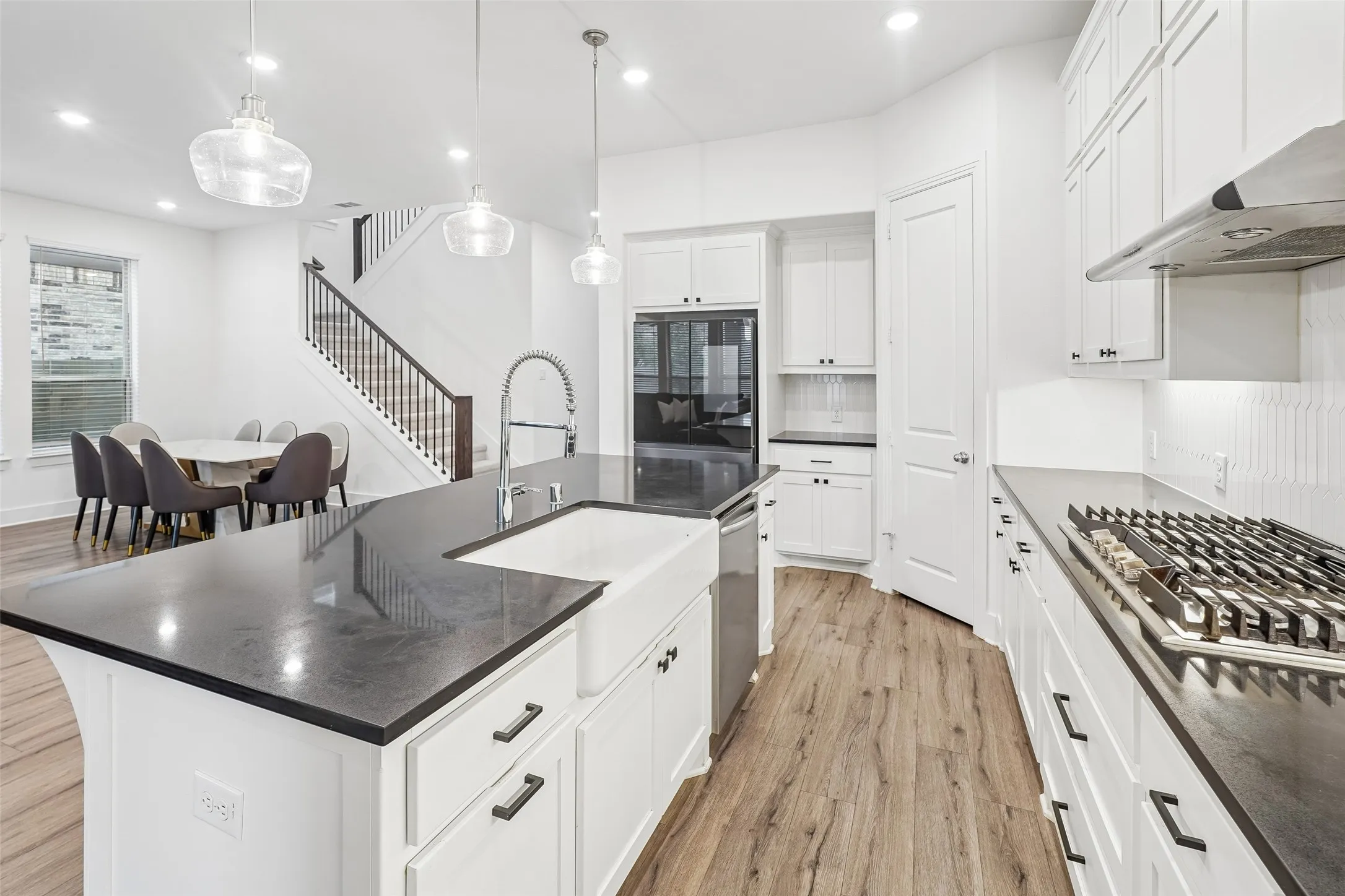 Gourmet kitchen with dark countertops, white cabinetry, a built-in range, and wood-finish flooring