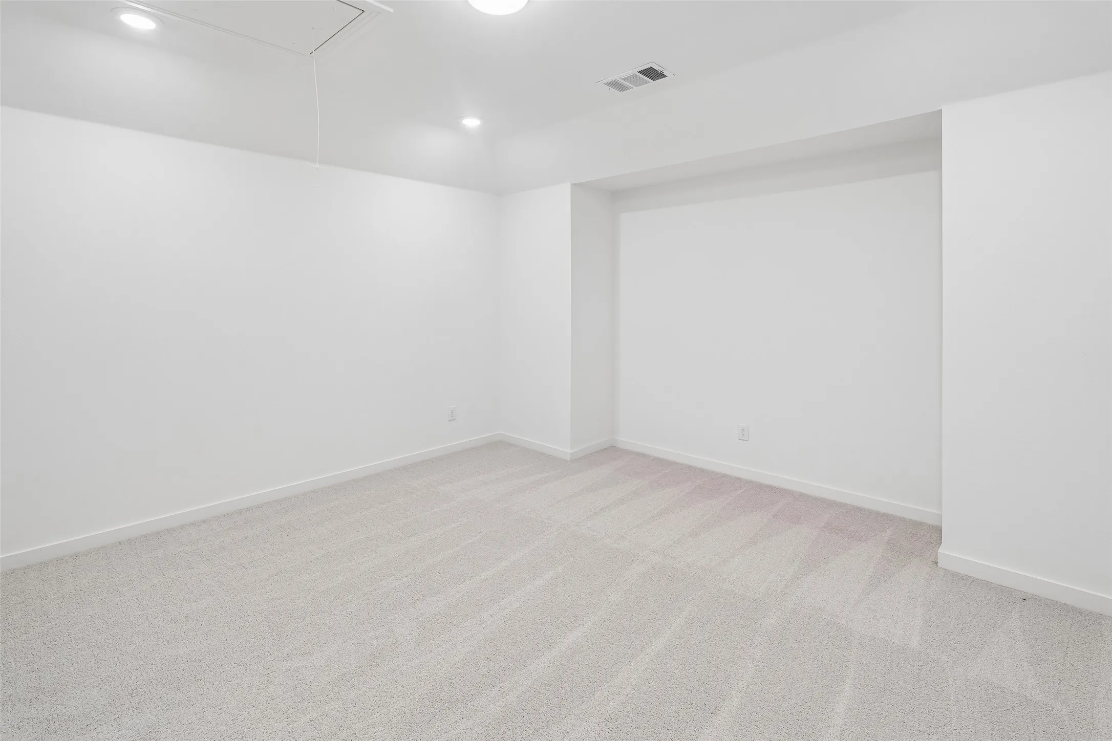 Recessed lighting illuminates the space, featuring light-toned carpeting and neutral walls
