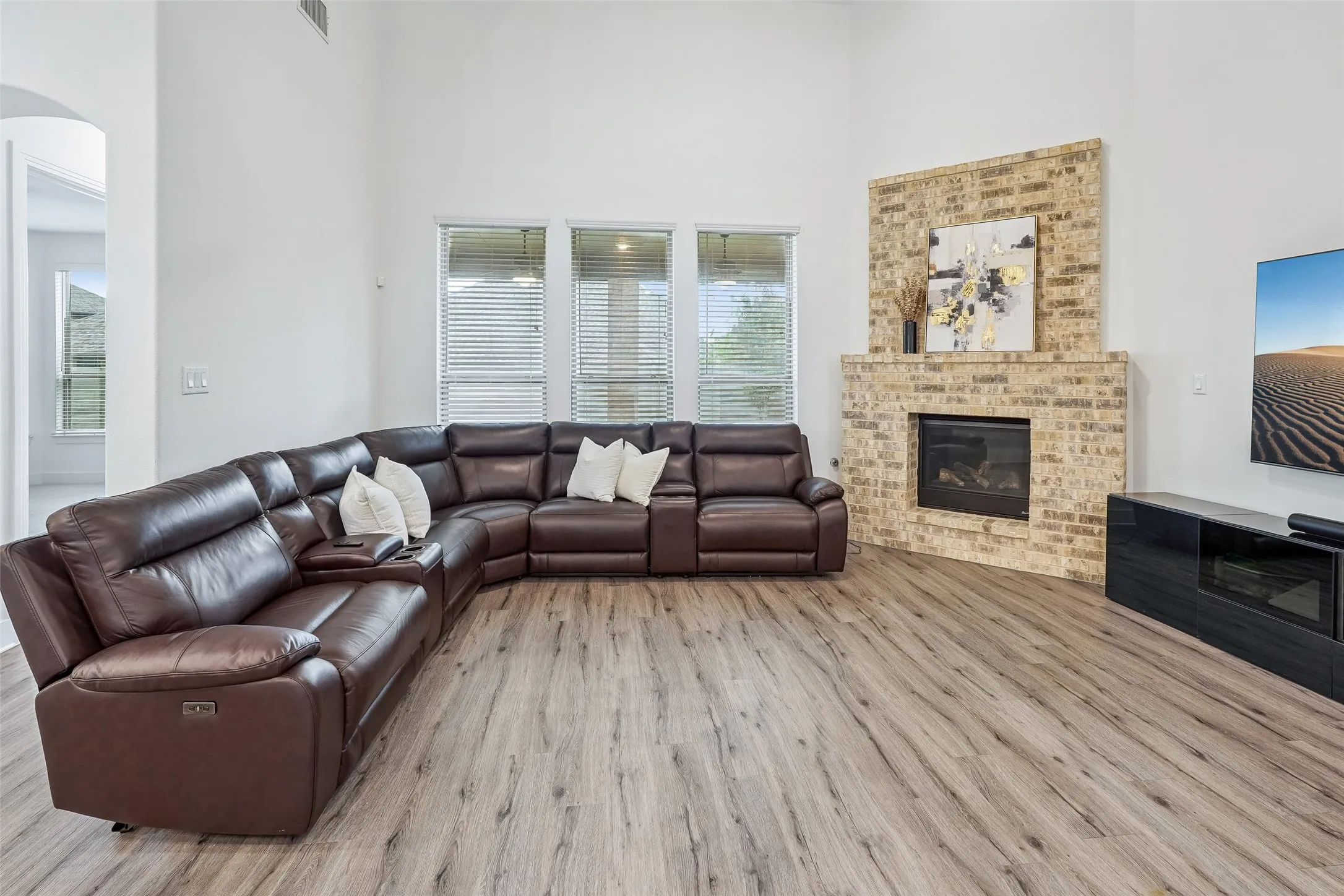 Vaulted ceiling, wood-finish flooring, brick fireplace with mantel, and large windows