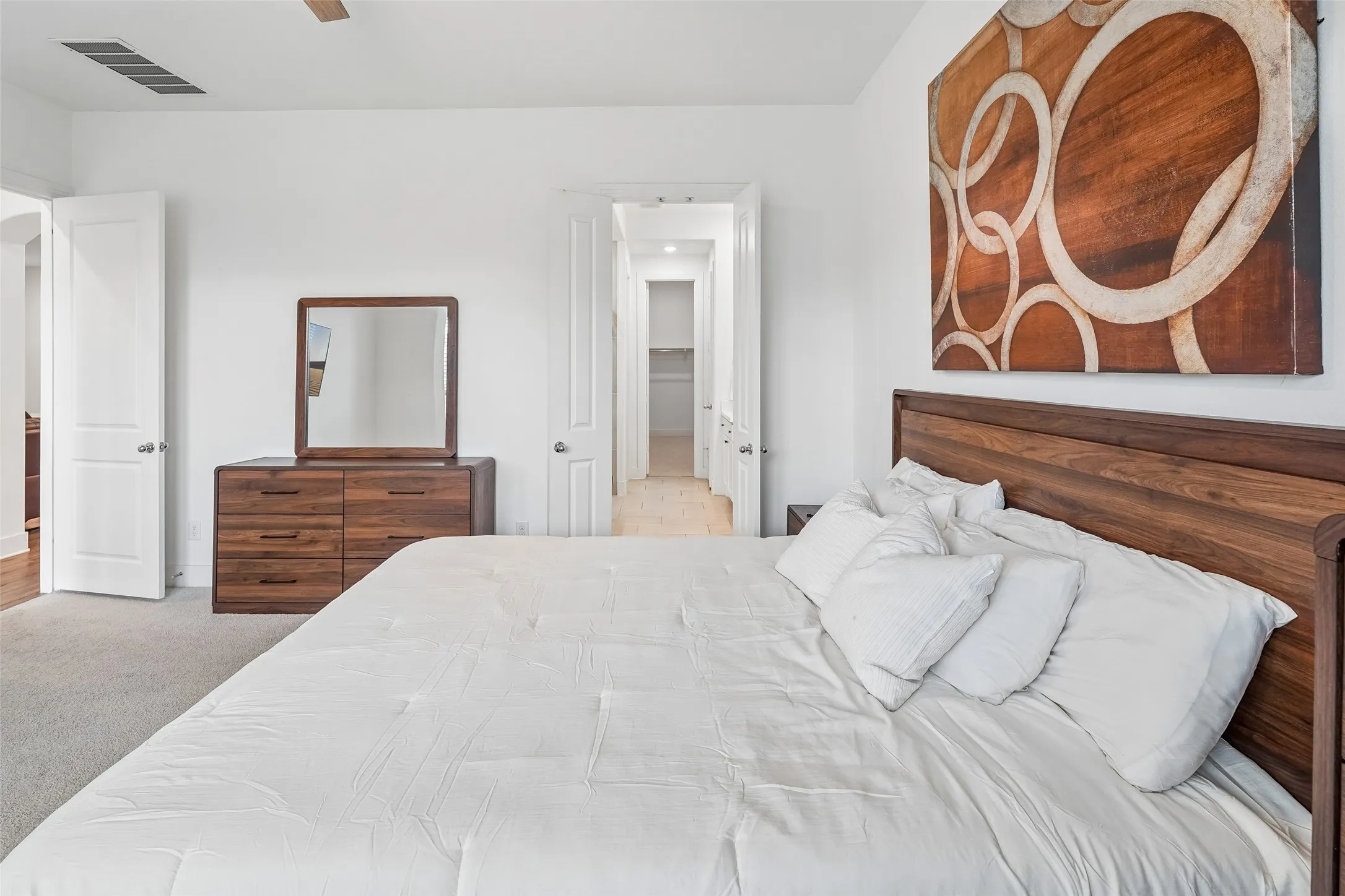 Carpeted flooring, white walls, and a light wood-finish ceiling fan