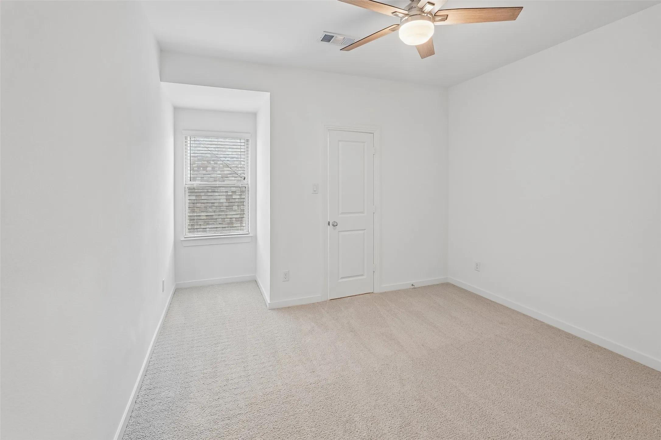 Recessed window with blinds, ceiling fan with integrated lighting, and neutral carpeting