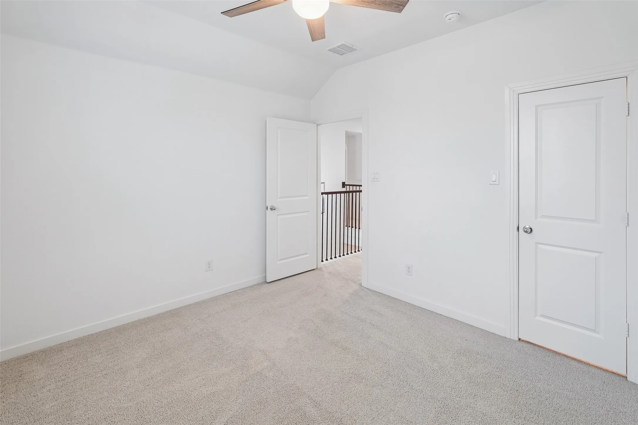 White walls, light-toned carpeting, white interior doors, and a ceiling fan