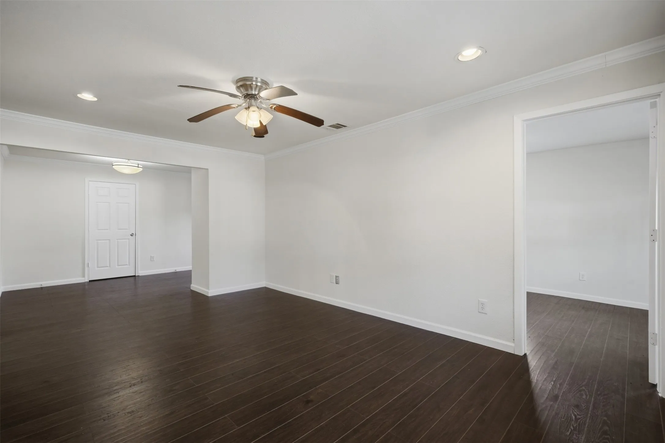 Dark wood-finish flooring, ceiling fan with integrated lighting, recessed lighting, white trim, and a paneled interior door