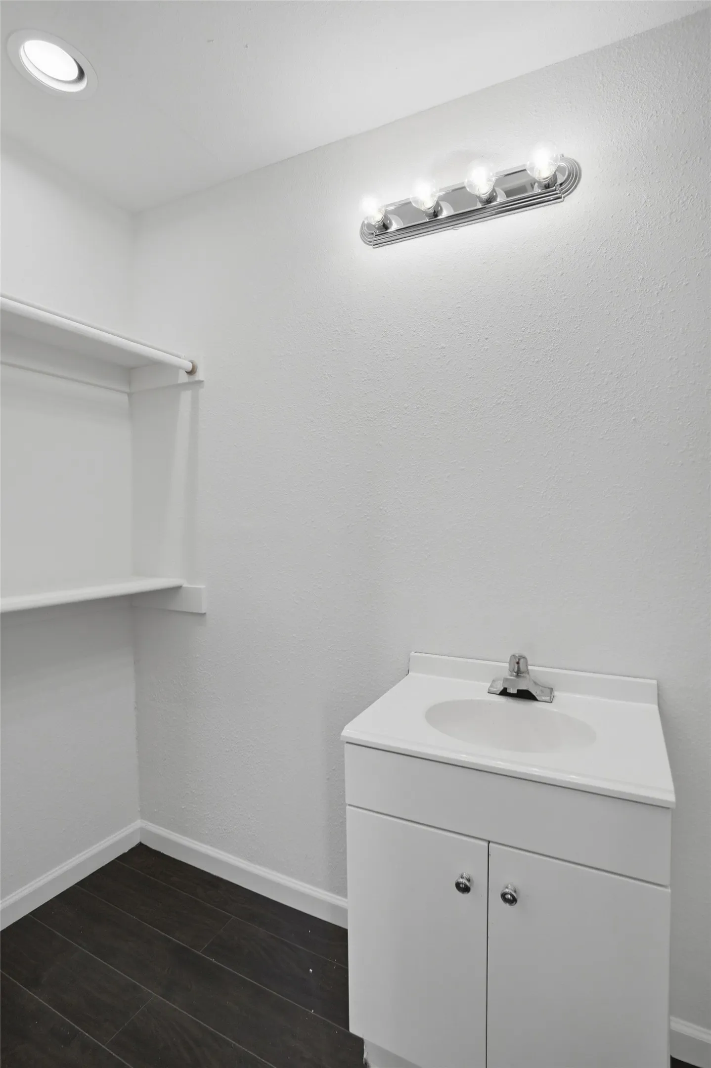 White vanity with a built-in sink, chrome faucet, and storage cabinetry