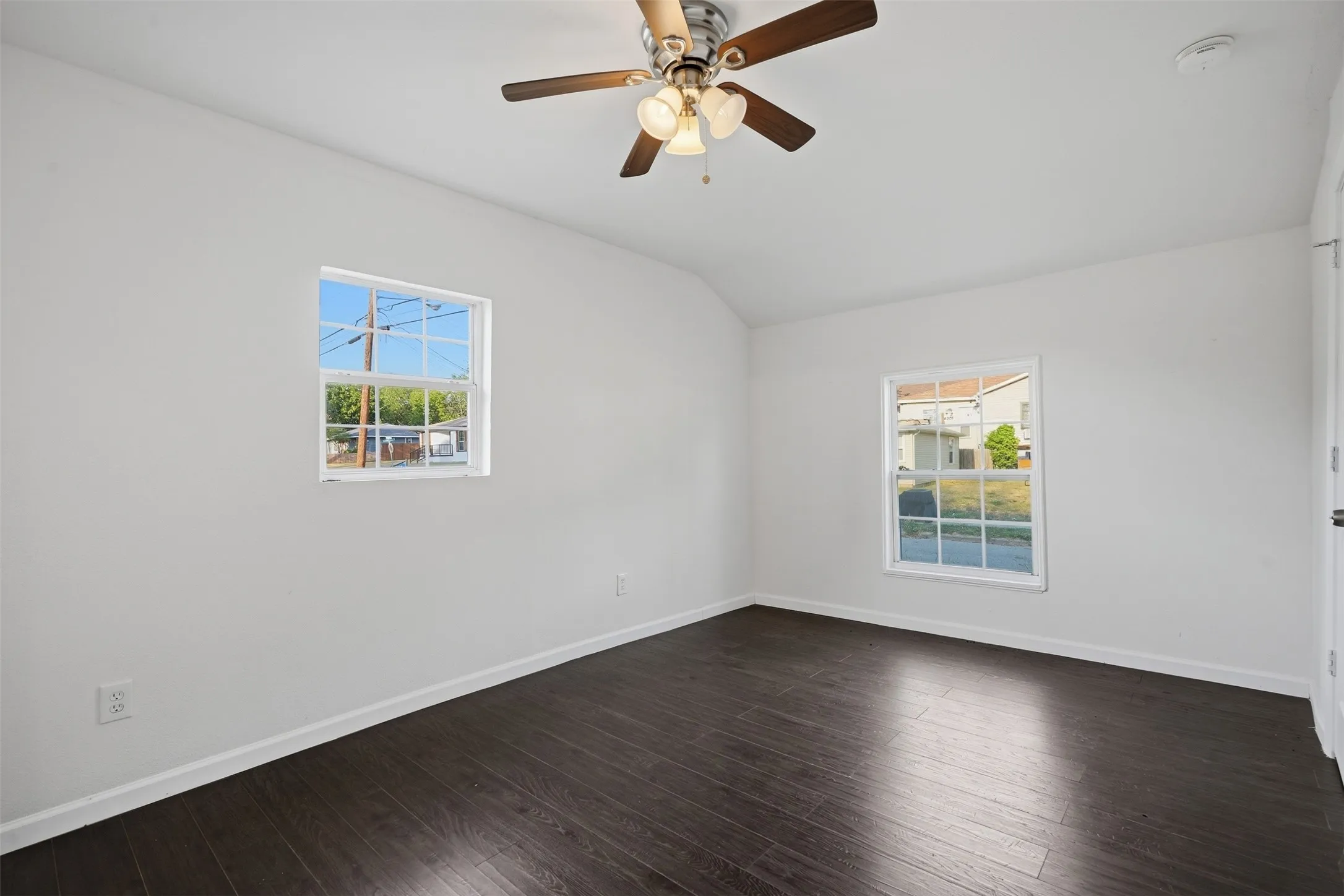 Dark wood-finish flooring, white walls, and a ceiling fan with light fixture