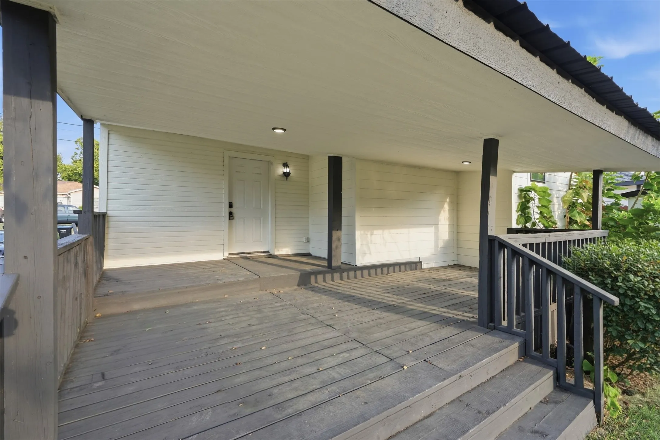 Covered deck with composite wood-finish flooring, black metal railings, and recessed ceiling lighting