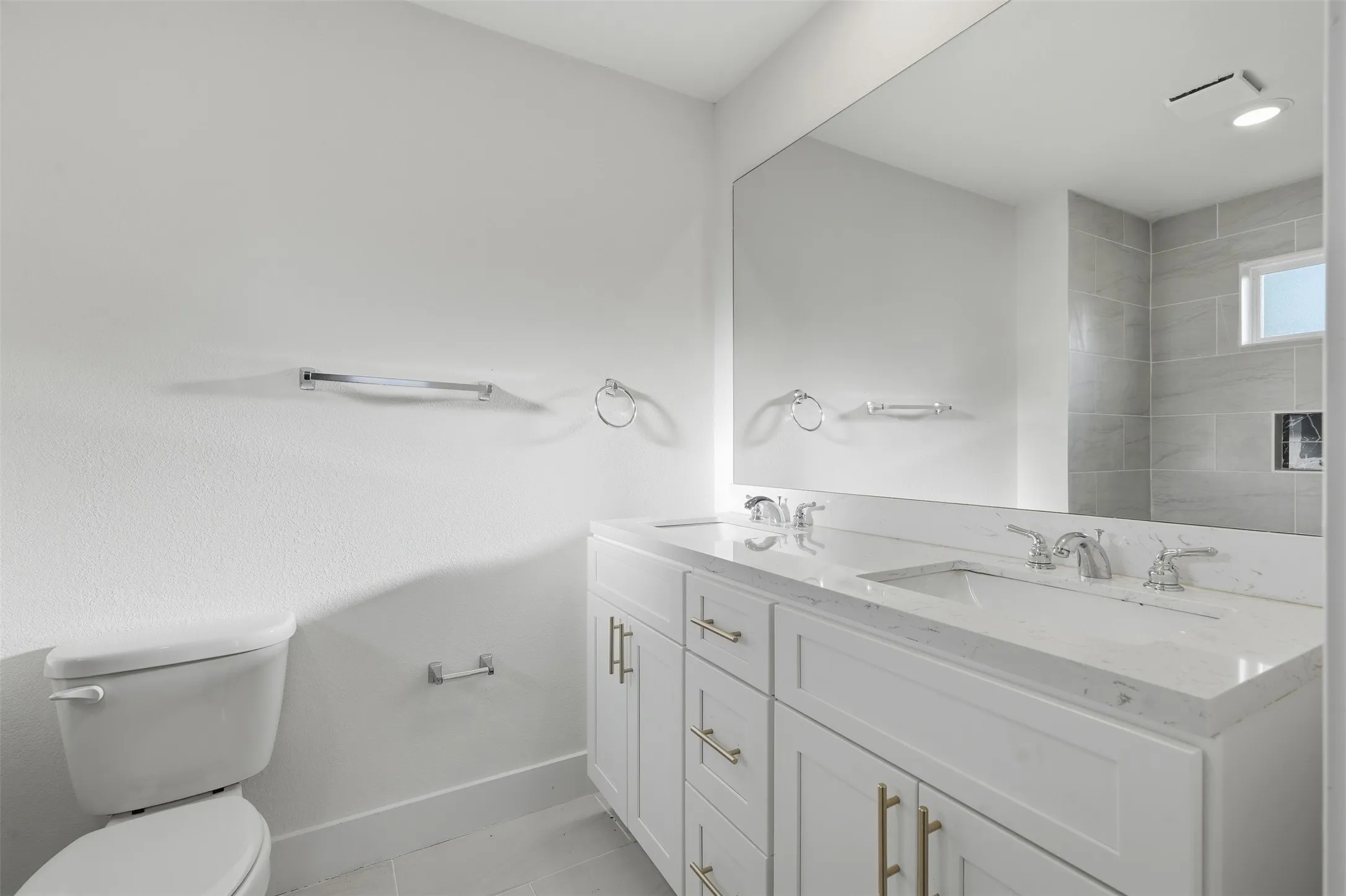 Dual vanity with white cabinetry, polished chrome fixtures, and a large integrated mirror