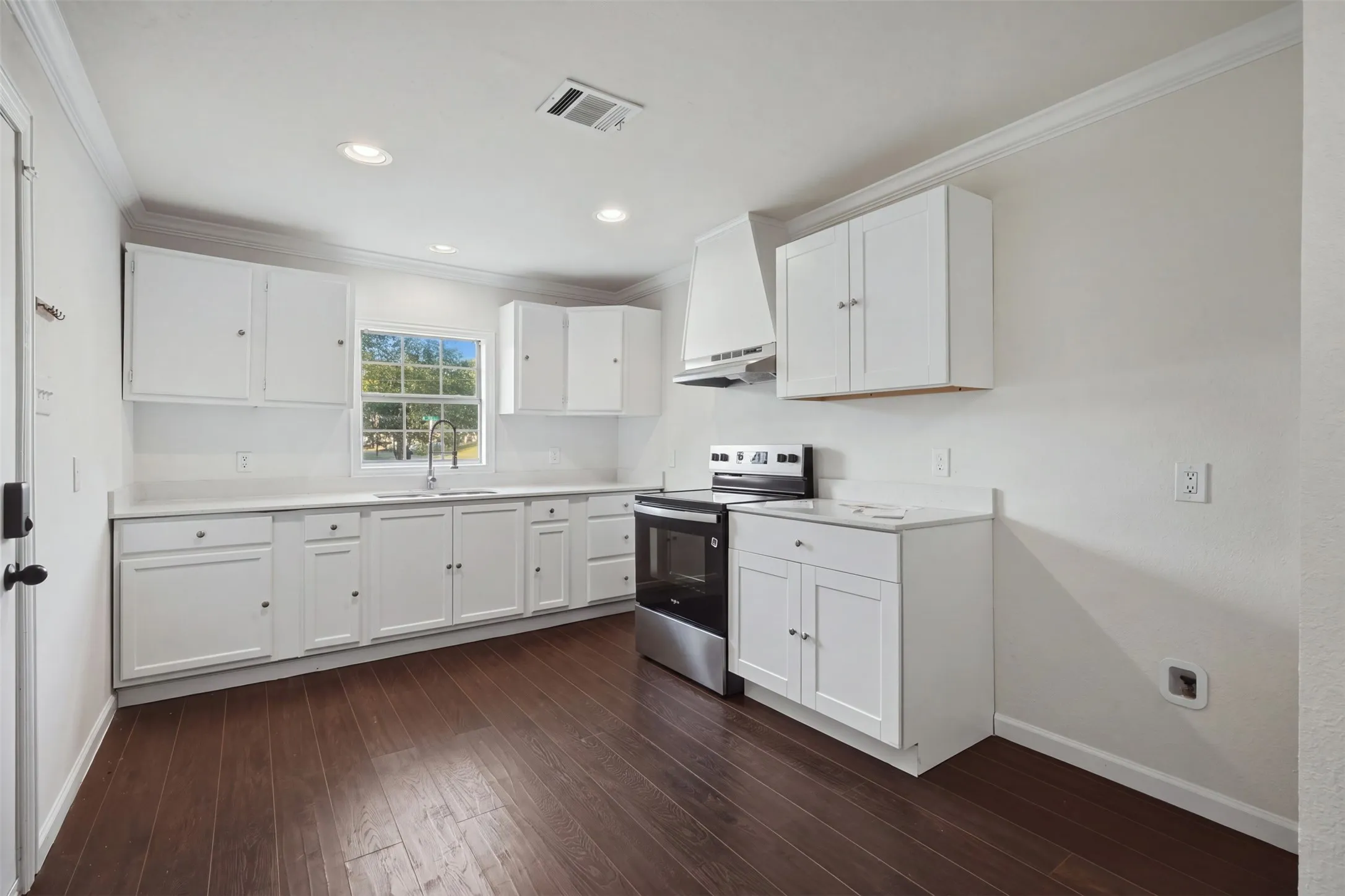 Kitchen featuring rich wood-finish flooring, white cabinetry, light countertops, and recessed lighting