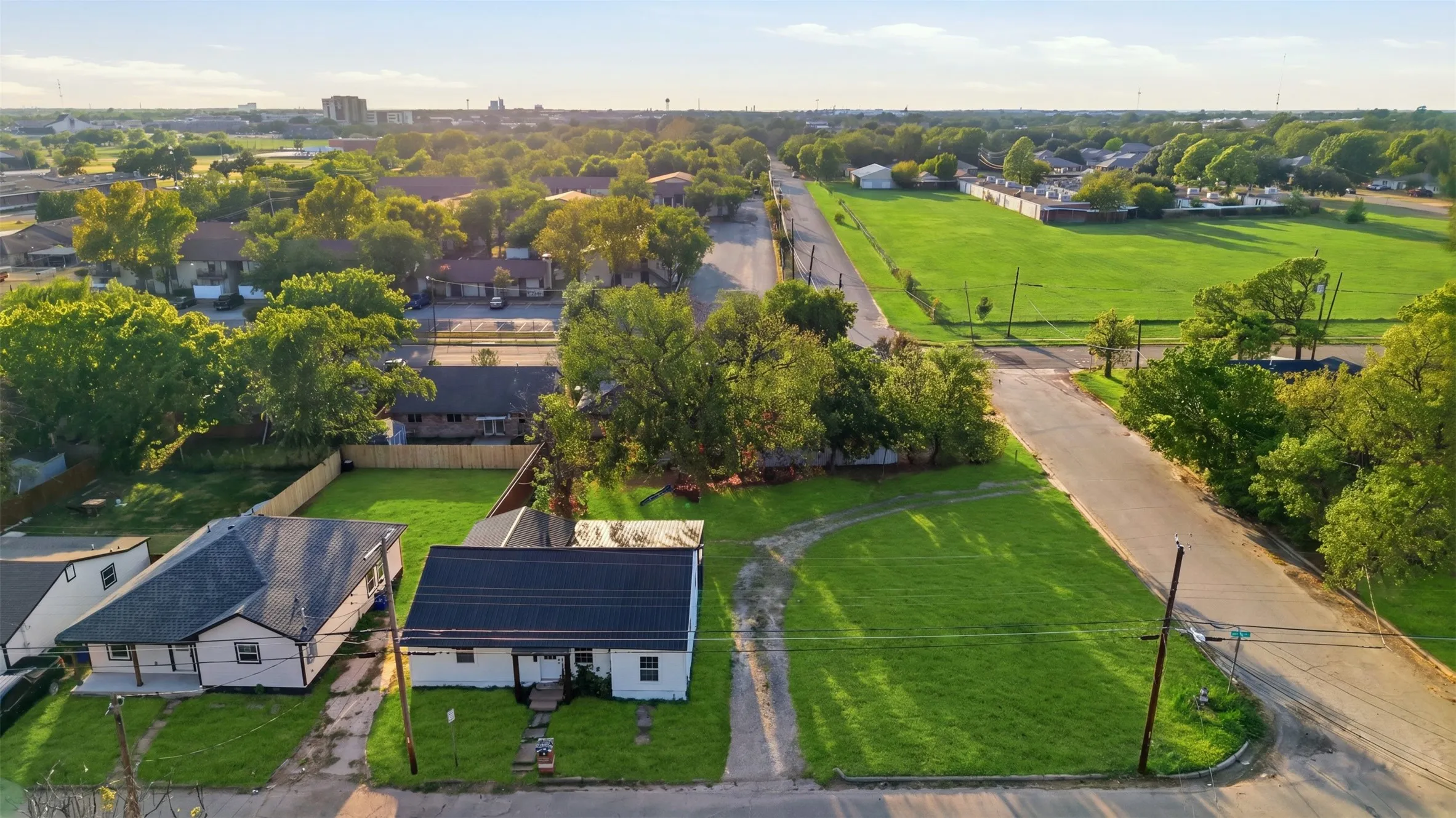 Expansive lot with lush green lawn, bordered by mature trees and a residential street