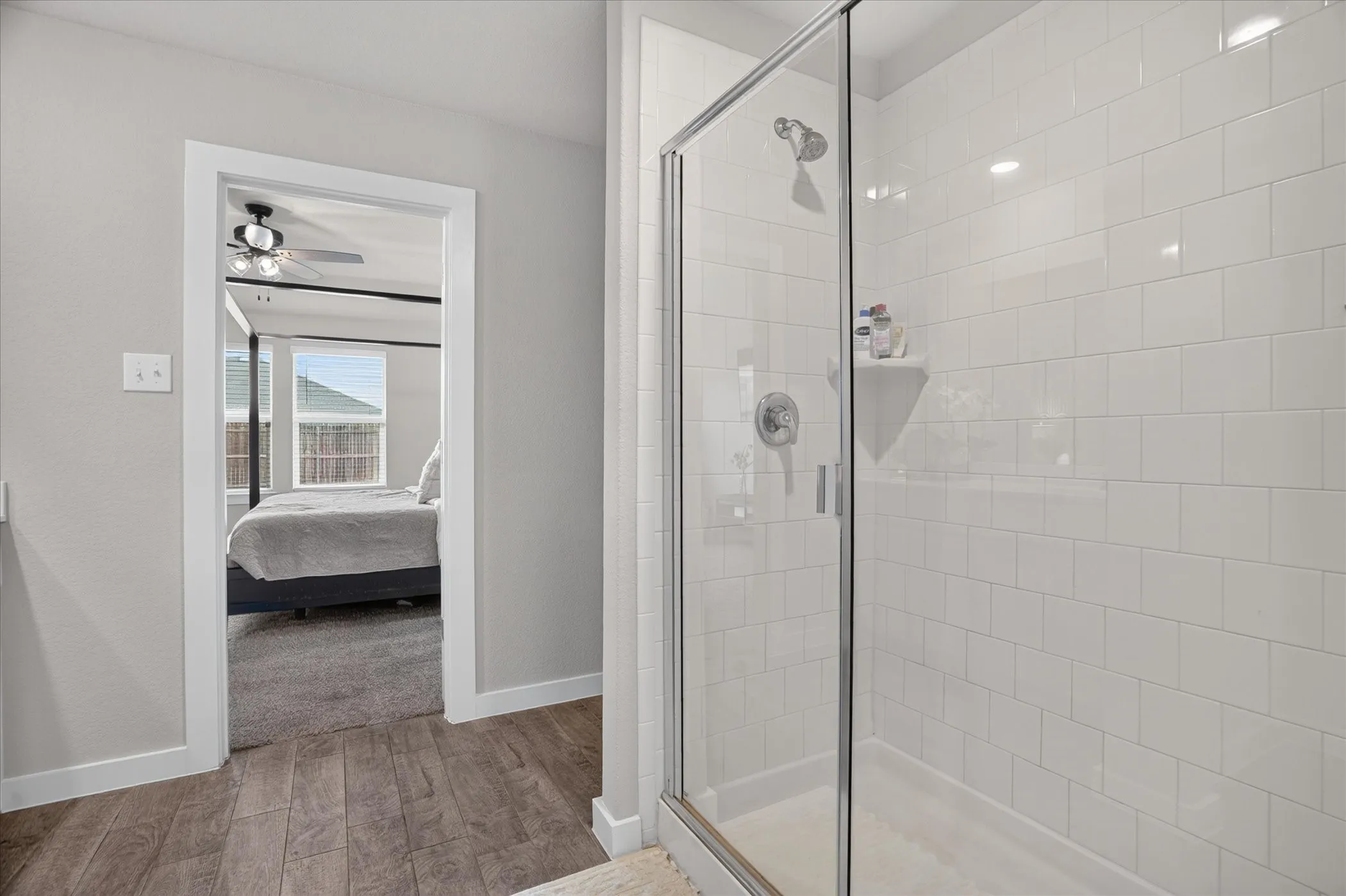 Walk-in shower with clear glass enclosure, white subway tile surround, and a built-in corner shelf