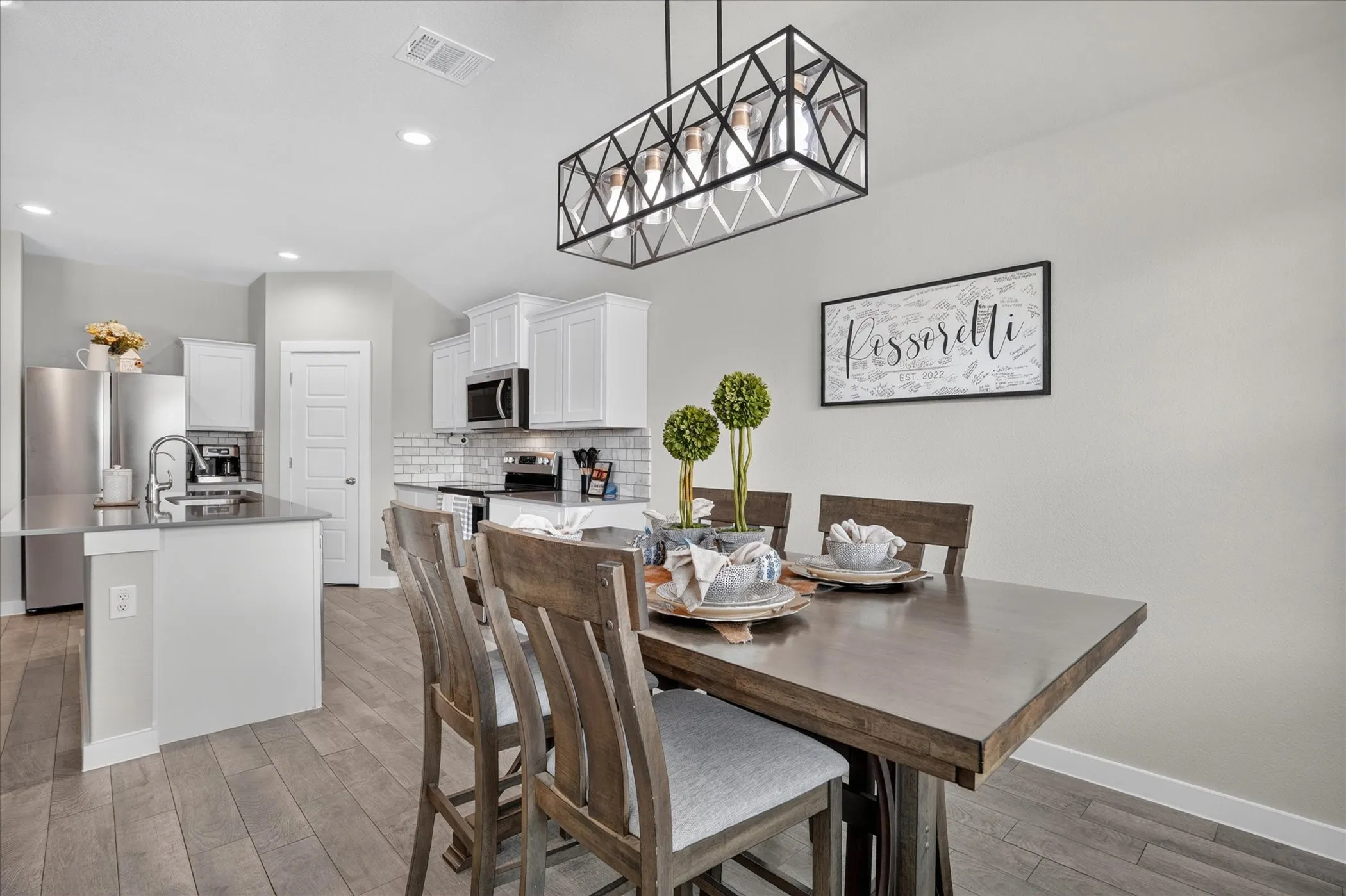 Dining area with wood-finish flooring, a linear geometric chandelier, and an open concept layout