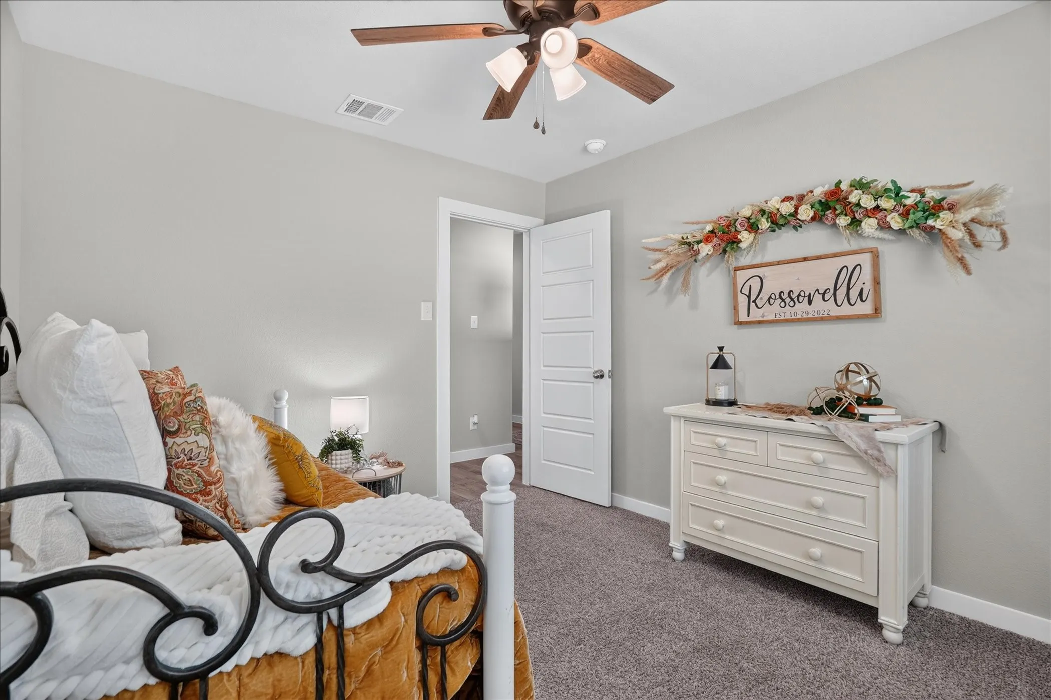 Carpeted flooring, a ceiling fan with light fixture, and a five-panel interior door