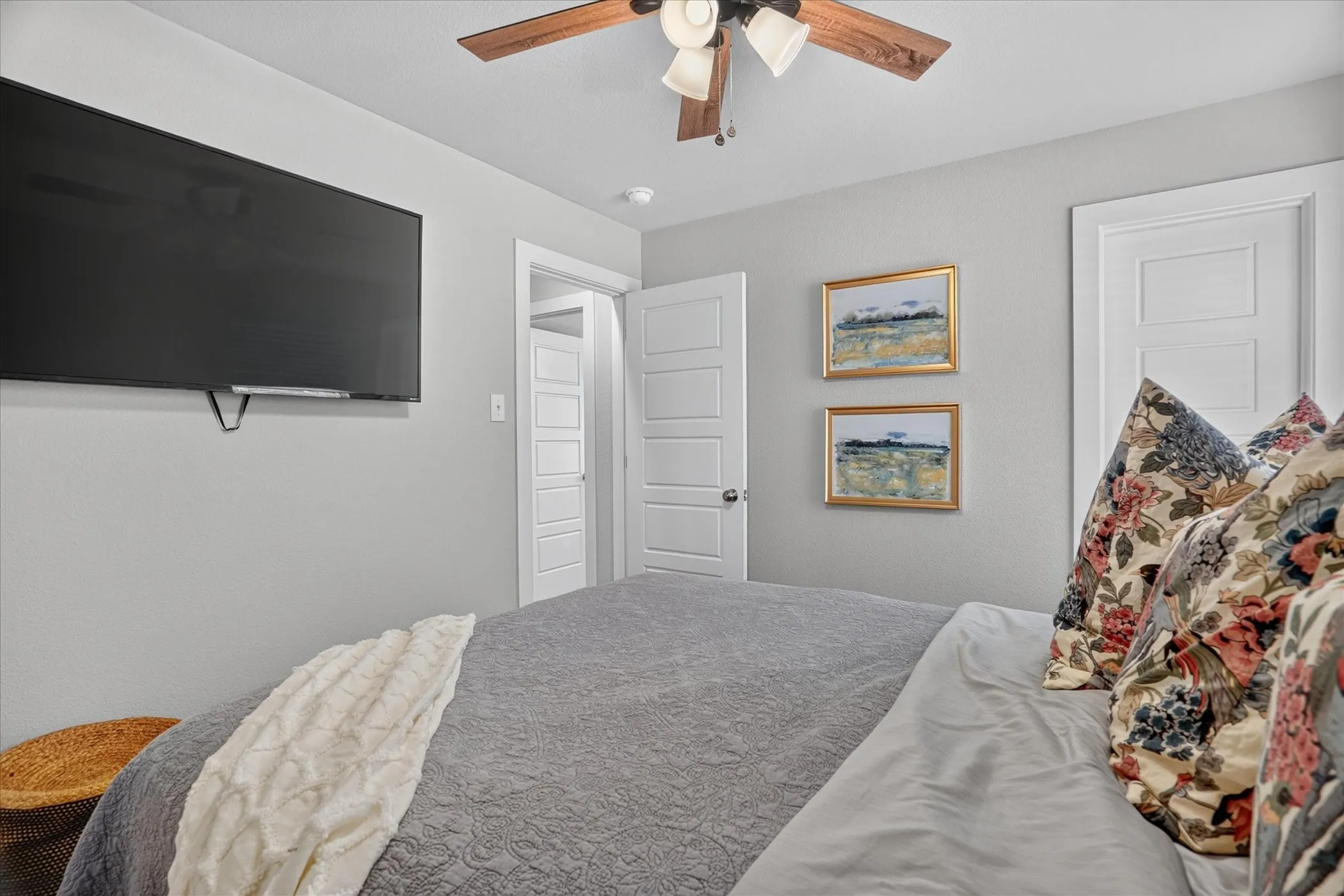 Wall-mounted television, wood-finish ceiling fan, recessed lighting, and a five-panel interior door