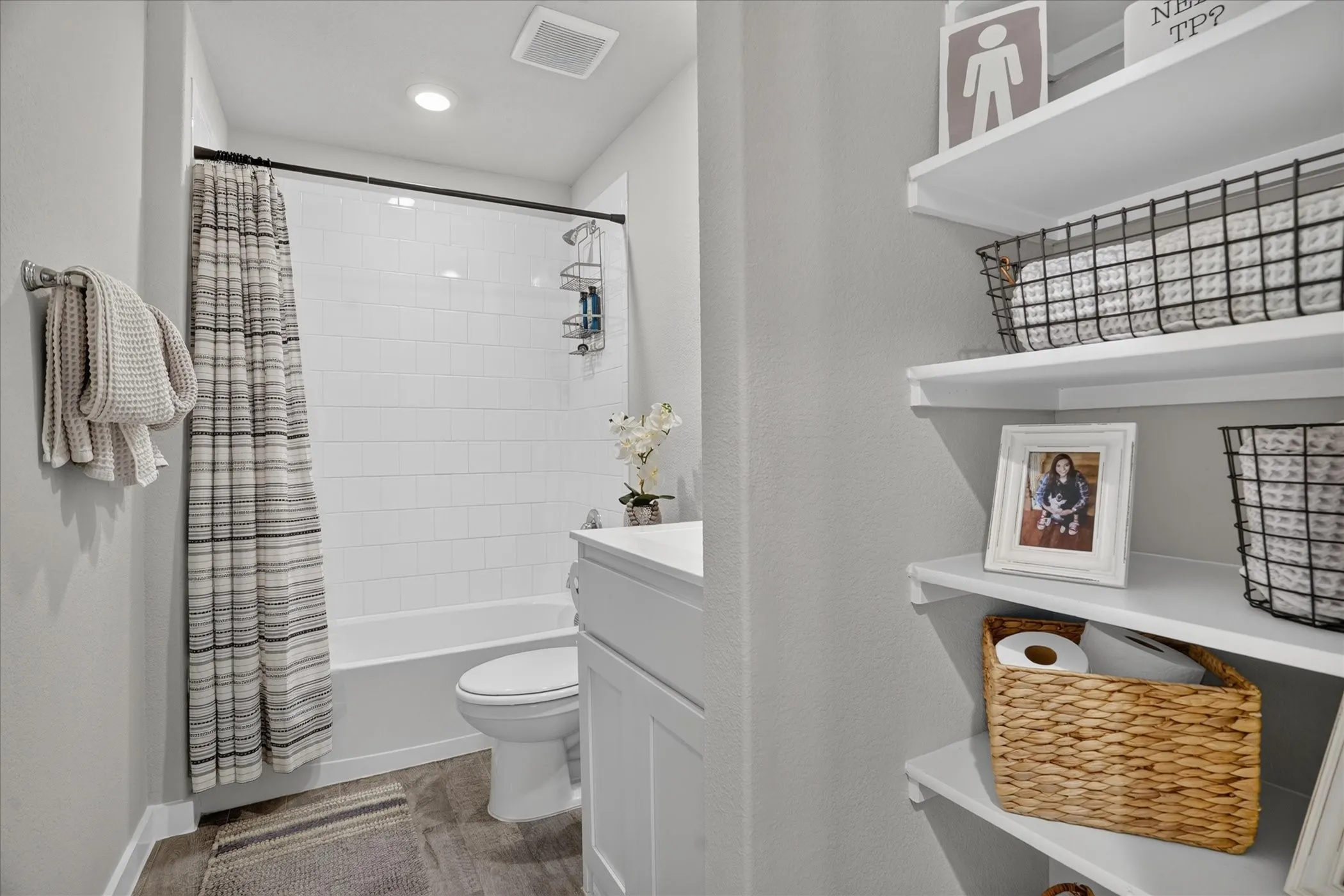 White subway tile shower surround with a built-in tub, recessed lighting, and wood-finish flooring