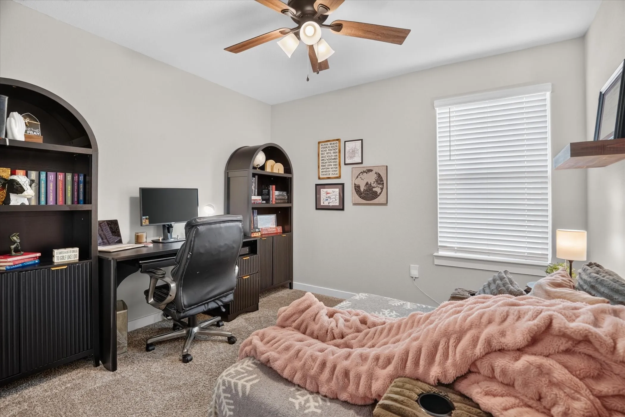 Recessed window with blinds, wood-finish ceiling fan with lighting, light-colored walls, and carpeting, bedroom is separate from other 2 bedrooms across from utility room.