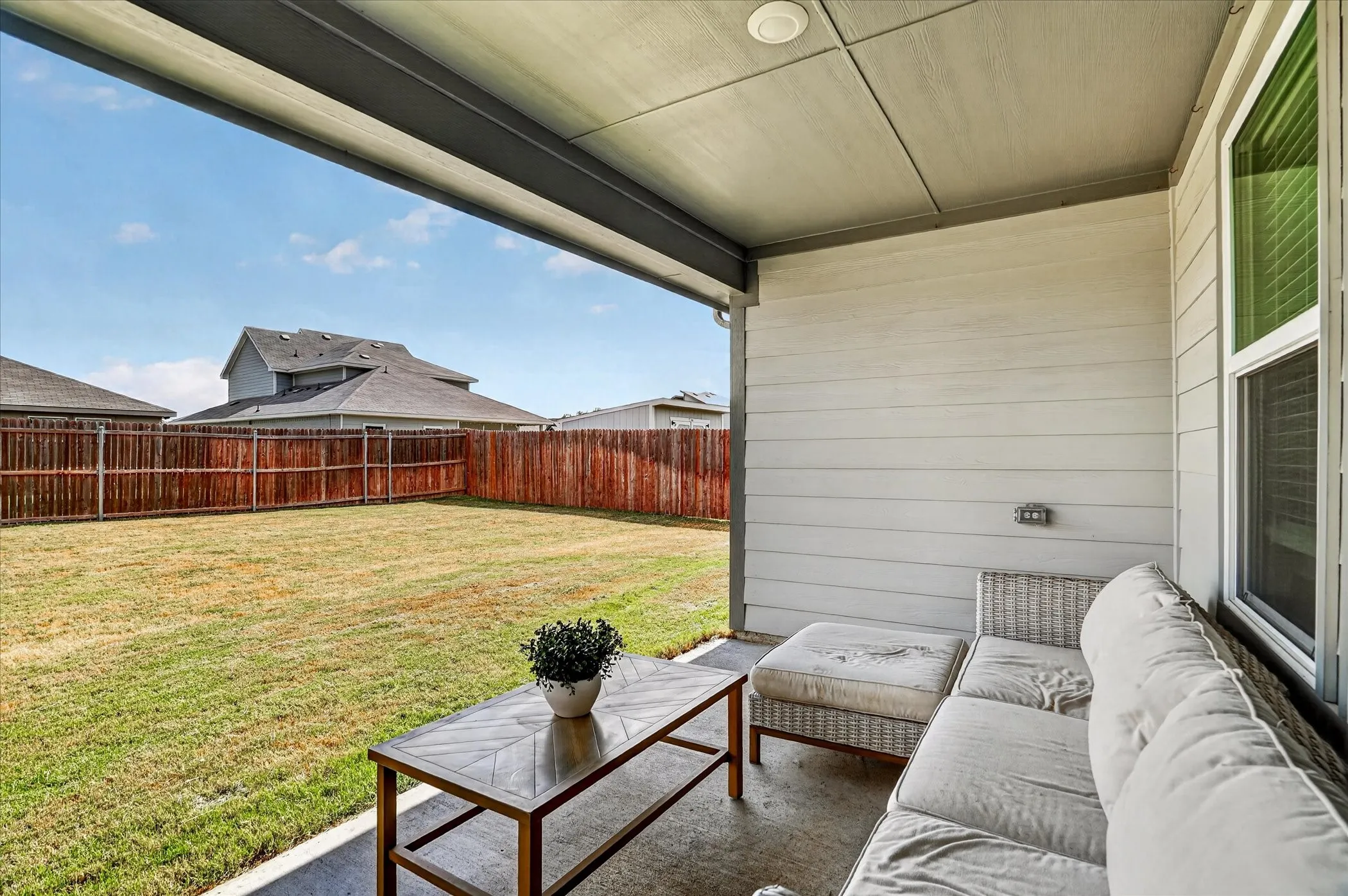 Covered patio with concrete flooring, wood-paneled siding, and a white framed window