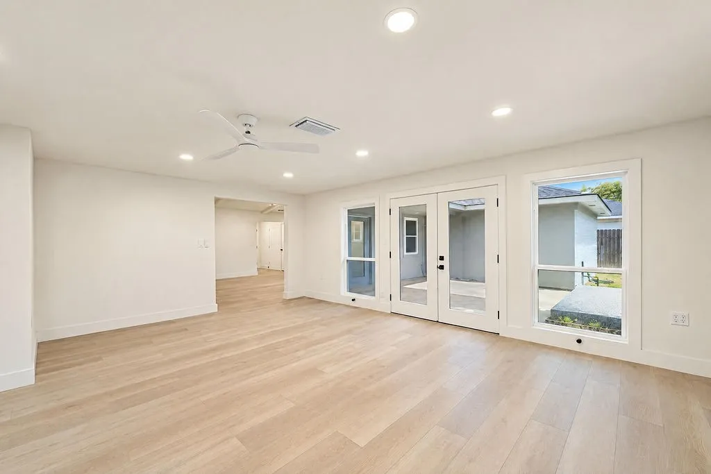 Recessed lighting, light wood-finish flooring, white walls, white ceiling fan, and double glass-paneled doors