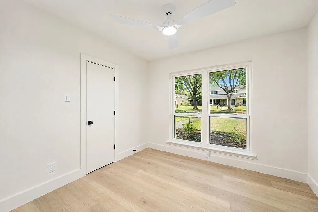 Light wood-finish flooring, white walls, and a contemporary ceiling fan with integrated lighting