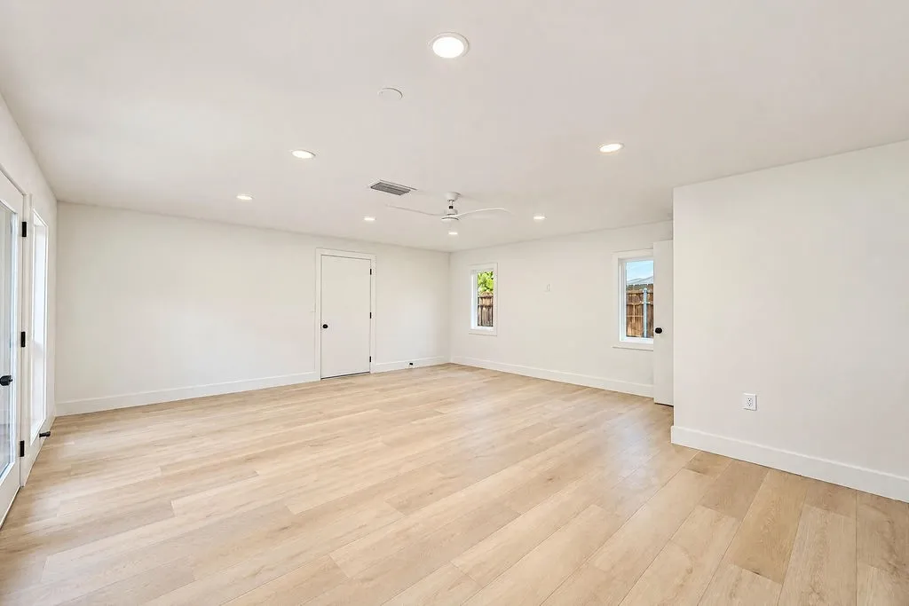 Spacious room featuring wood-finish flooring, recessed lighting, and a ceiling fan