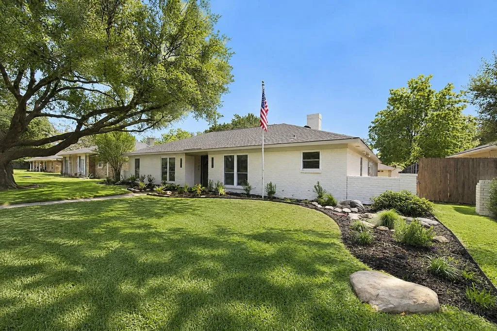 Single-story residence featuring a white brick exterior and a dark shingle roof