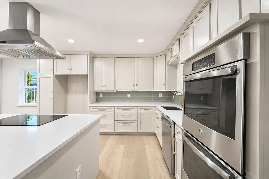 Modern kitchen featuring light cabinetry, stainless steel appliances, a center island with cooktop, and light wood-finish flooring