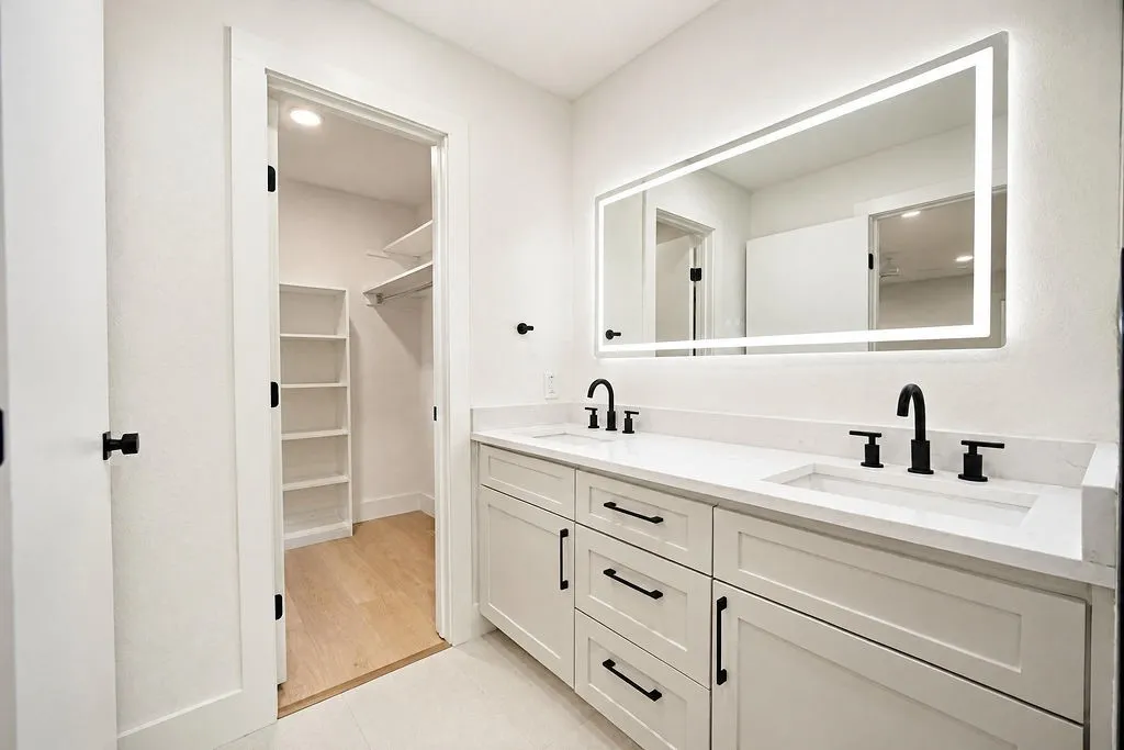 Dual vanity with undermount sinks, stone countertops, and matte black fixtures